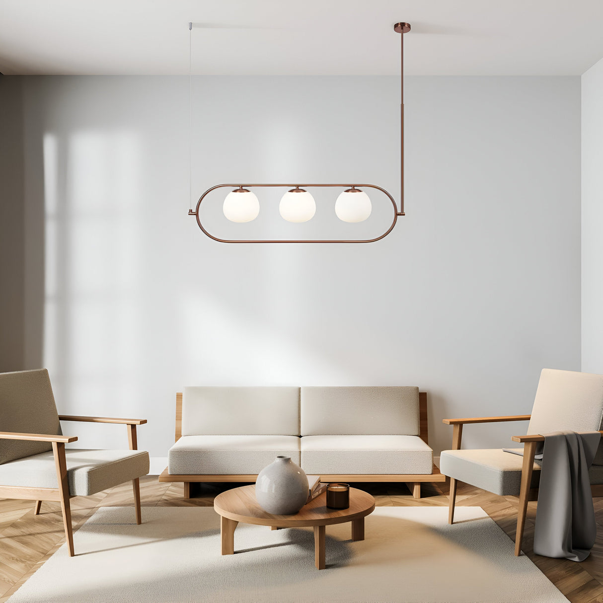 A minimalist living room featuring beige armchairs and a matching sofa around a small wooden coffee table. A vase rests on the table under the Erich 3 Light Suspension in brass with white glass shades. Sunlight from the left highlights its modern and adjustable design.