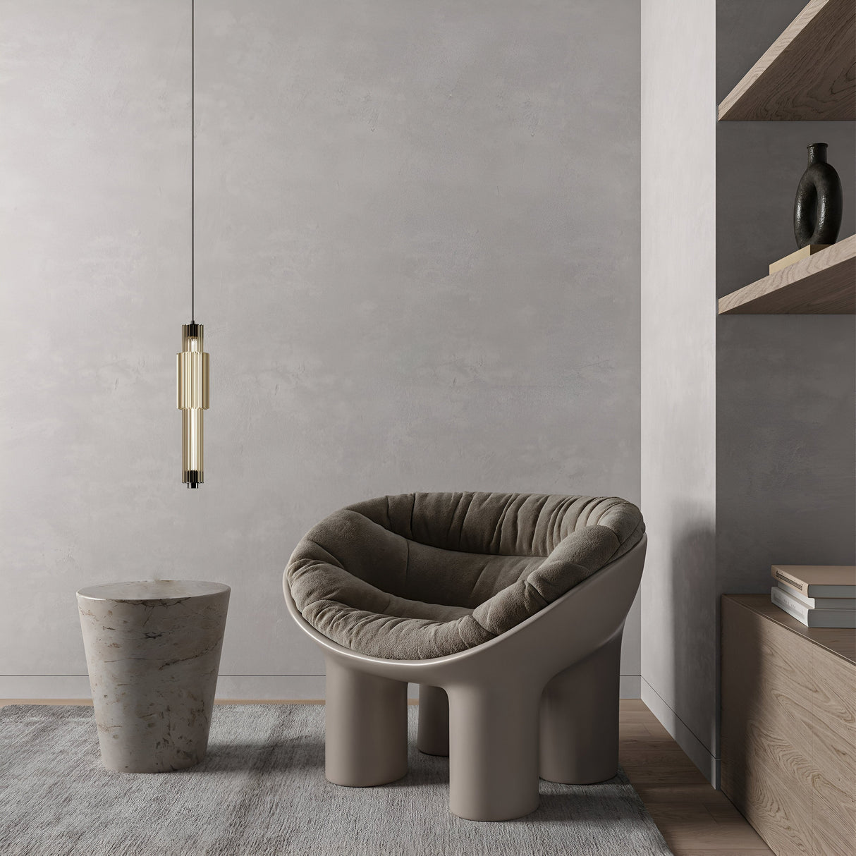 In a minimalist room, a gray cushioned chair and cylindrical marble side table rest on a gray rug. The Verticale LED Pendant Light 3000K 8W - Chrome With Cognac Ribbed Glass hangs above. A wooden shelf with books and a vase is set against the textured gray wall to the right.