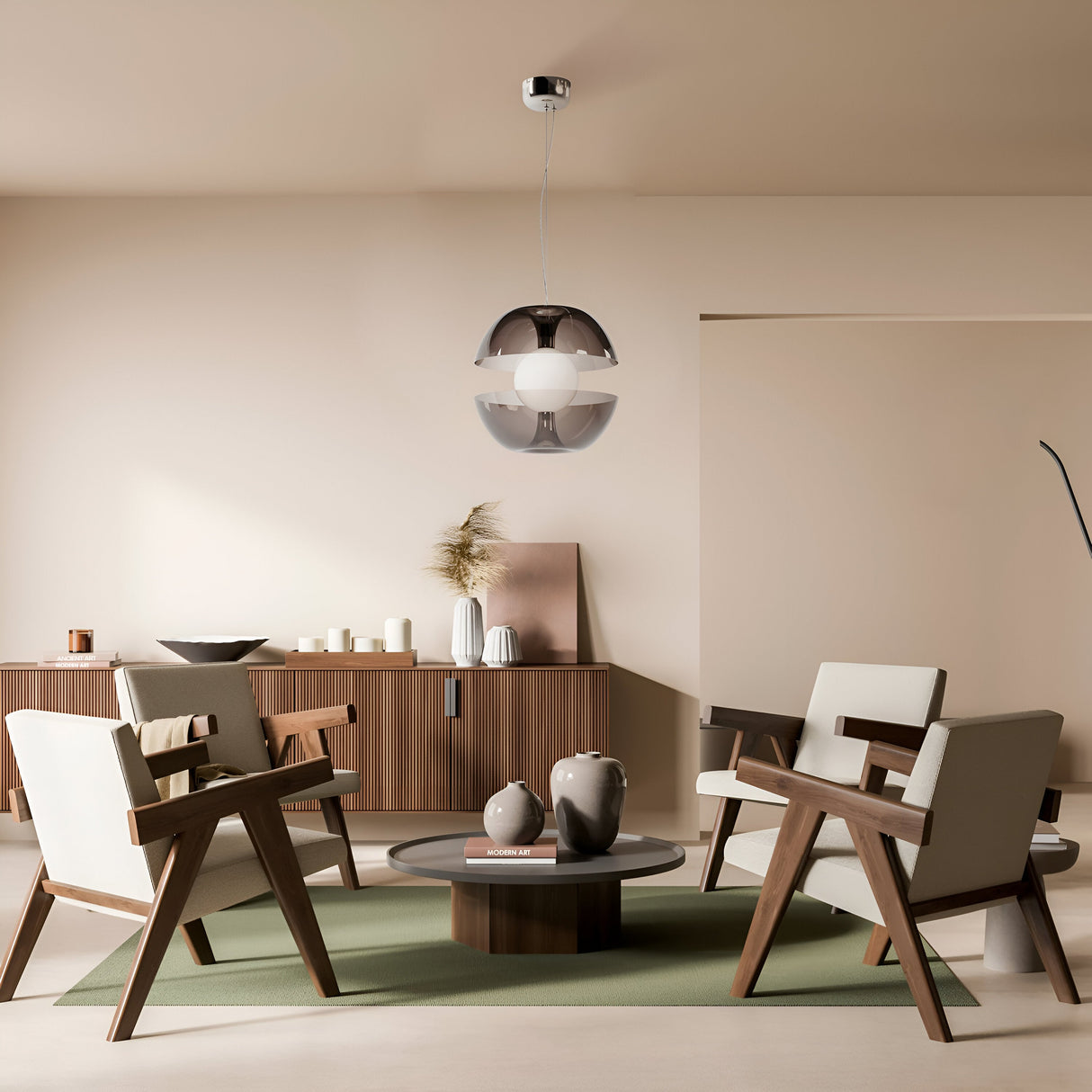 A minimalist living room features four wooden chairs around a round table on a green rug, illuminated by a Rebel LED Glass Pendant Light - Chrome. The room showcases beige walls and a sideboard adorned with vases and plants, adding elegance and simplicity.