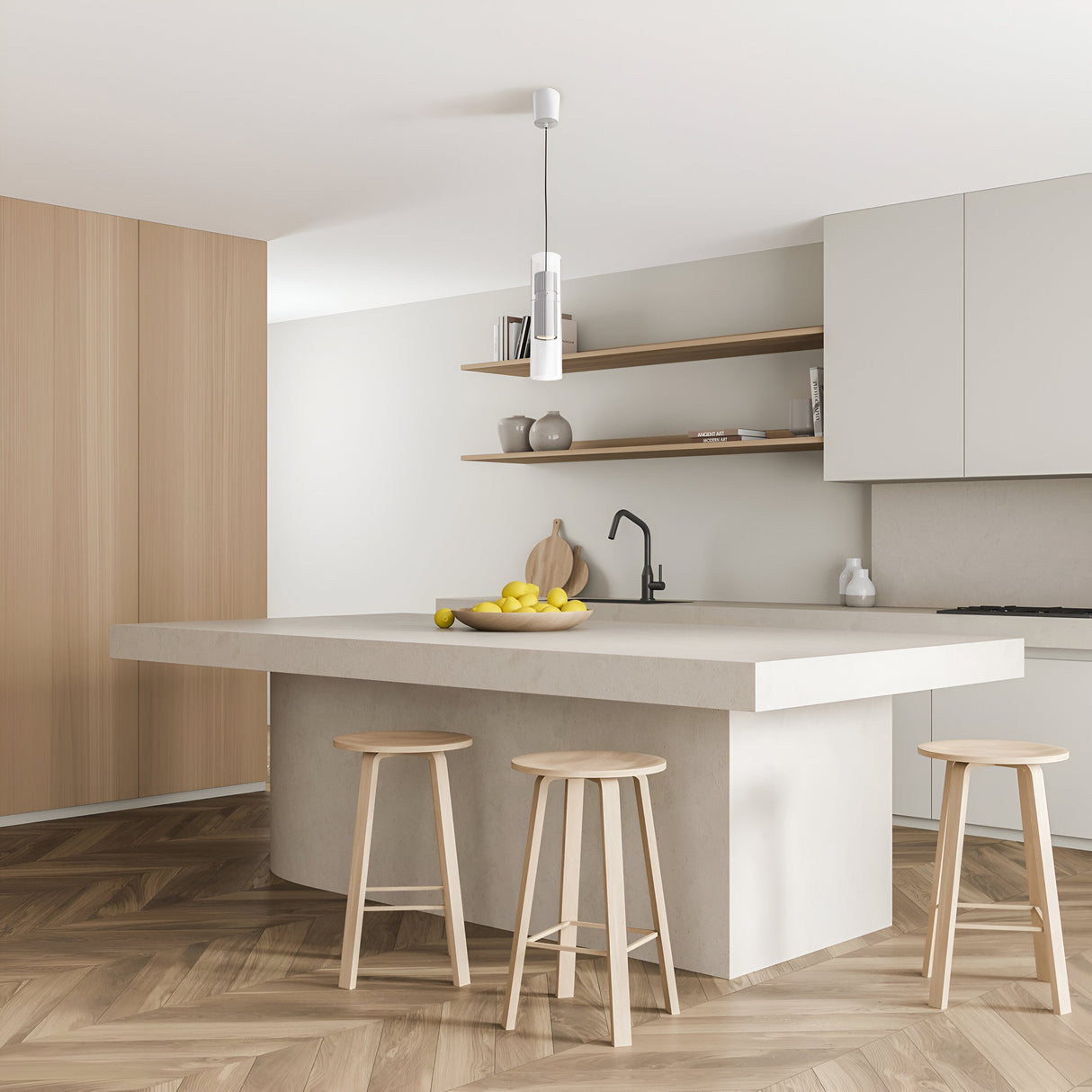 A minimalist kitchen features white walls, wood accents, a large island with light wood stools, black faucet, open shelves adorned with lemons, and a herringbone floor. The look is completed by the Dynamics Pendant Light - White With Outer Clear Glass adding elegance above.