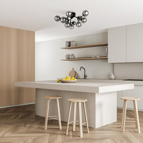Modern kitchen with a large white island, three wooden stools, and a bowl of lemons. Warmth is added by wooden wall paneling and herringbone parquet flooring. Minimalist shelving, contemporary lighting, and the Dallas 12 Light Semi-Flush - Black With Smoked Glass enhance the industrial-inspired design. .