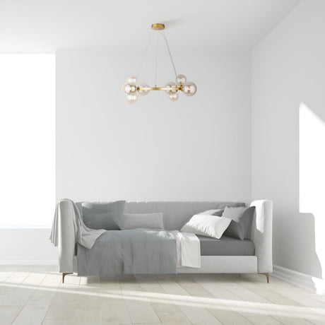 Minimalist living room with a light gray sofa, assorted pillows, and blankets. A modern Dallas 11 Light Suspension in gold with amber glass spheres hangs above. The wooden floor and large window create a bright, airy atmosphere.