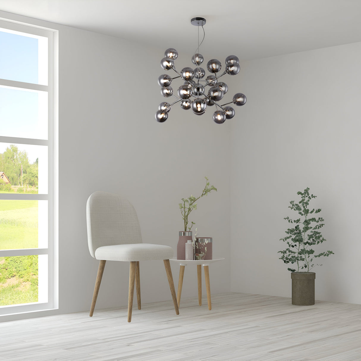 A minimalist room showcases a Chrome Dallas 24 Light Chandelier with smoky glass spheres, accompanied by a white chair with wooden legs, and a small round table adorned with vases and a potted plant. A large window to the left offers views of lush greenery. Light wood floors and white walls complete the look.