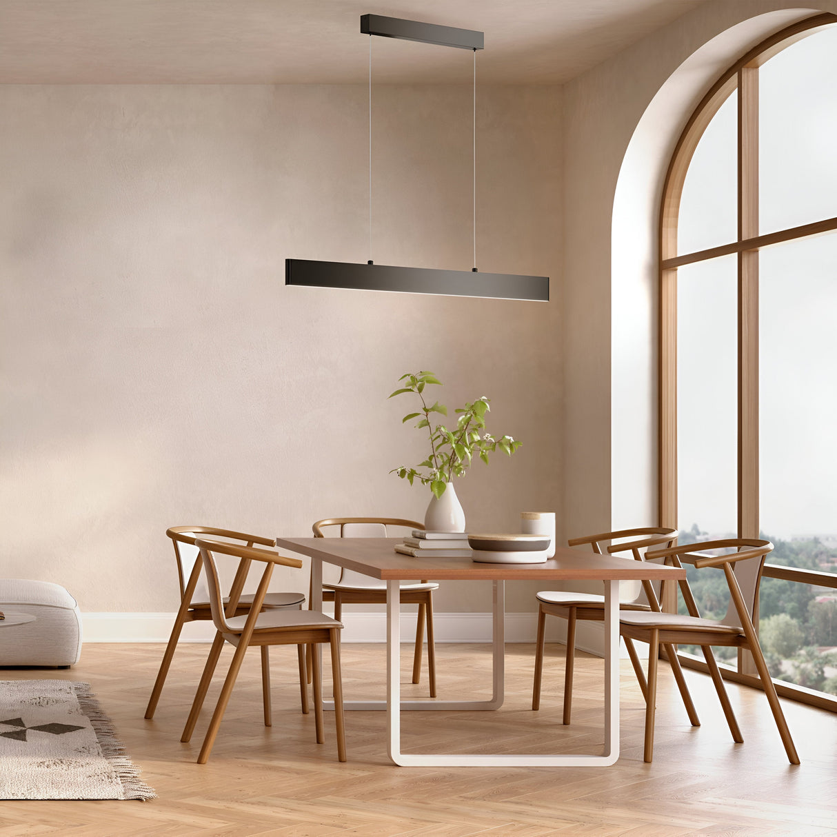 A modern dining room features a wooden table and four chairs under the Step LED Linear Suspension Light 4000K 30W - Black. A potted plant and tableware adorn the table. A large arched window floods the minimalist decor and parquet flooring with natural light.