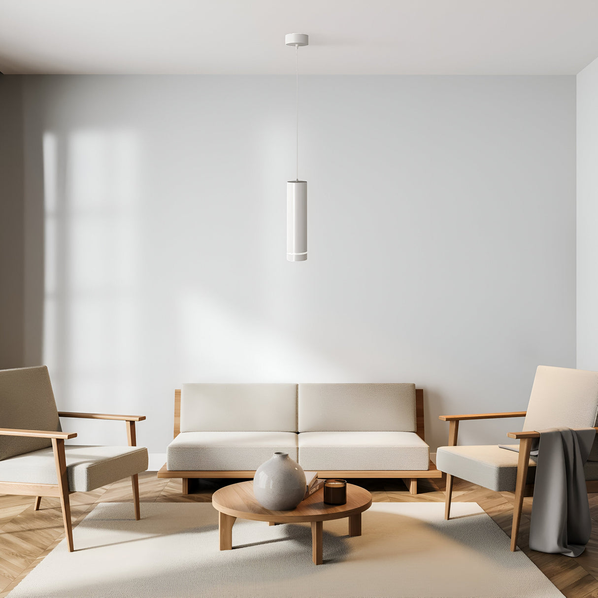 A minimalist living room showcases a white sofa and two beige armchairs with wooden frames. A round wooden coffee table holds a grey vase under the Orlo LED Pendant Light 3000K - White. Light wood flooring and large windows enhance the airy ambiance.