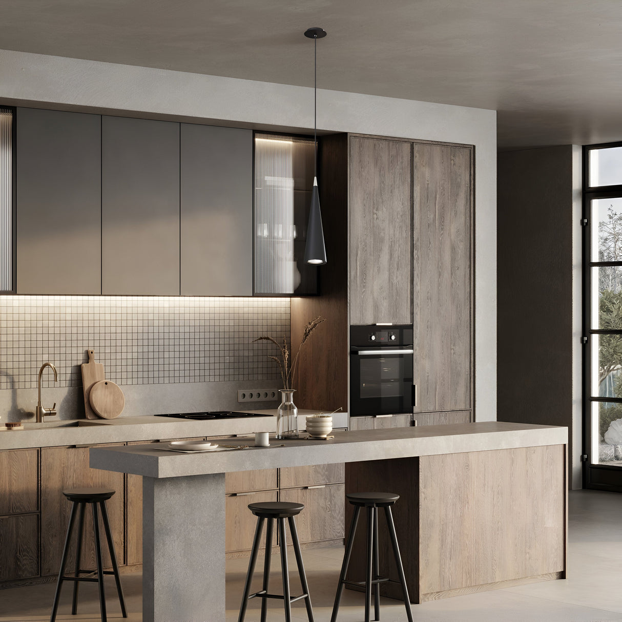 A modern kitchen with wooden cabinets, a concrete island, and black barstools features a Nevill Conical Pendant Light - Black. Its minimalist design includes a tiled backsplash, built-in oven, and large window that floods the space with natural light to enhance the sleek atmosphere.