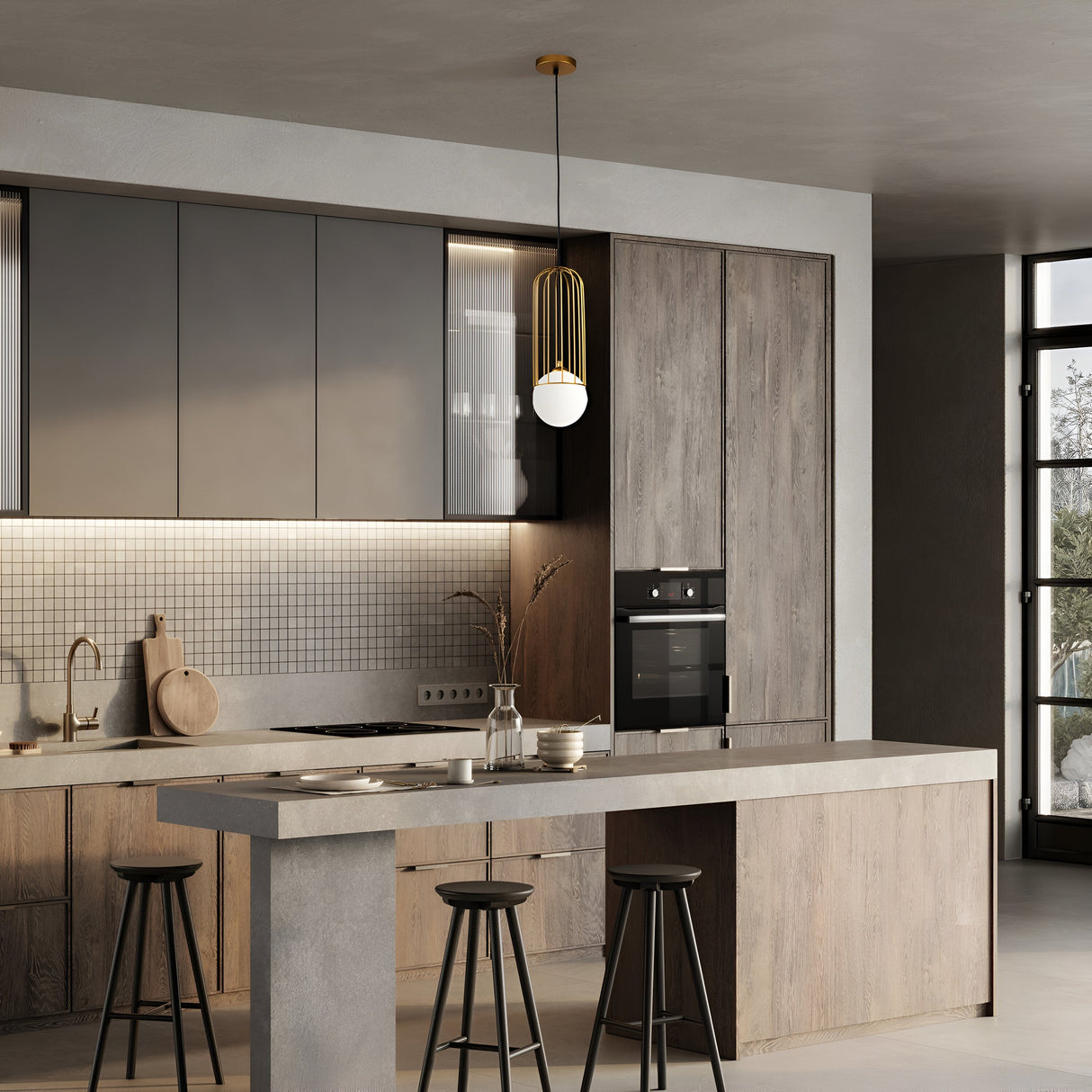 A modern kitchen with a minimalist design features a concrete island with three black stools. The back wall has wood cabinets, a built-in oven, and a tile backsplash. A Telford Pendant Light - Gold With Small White Glass adds an industrial edge above the island, and large windows let in natural light.