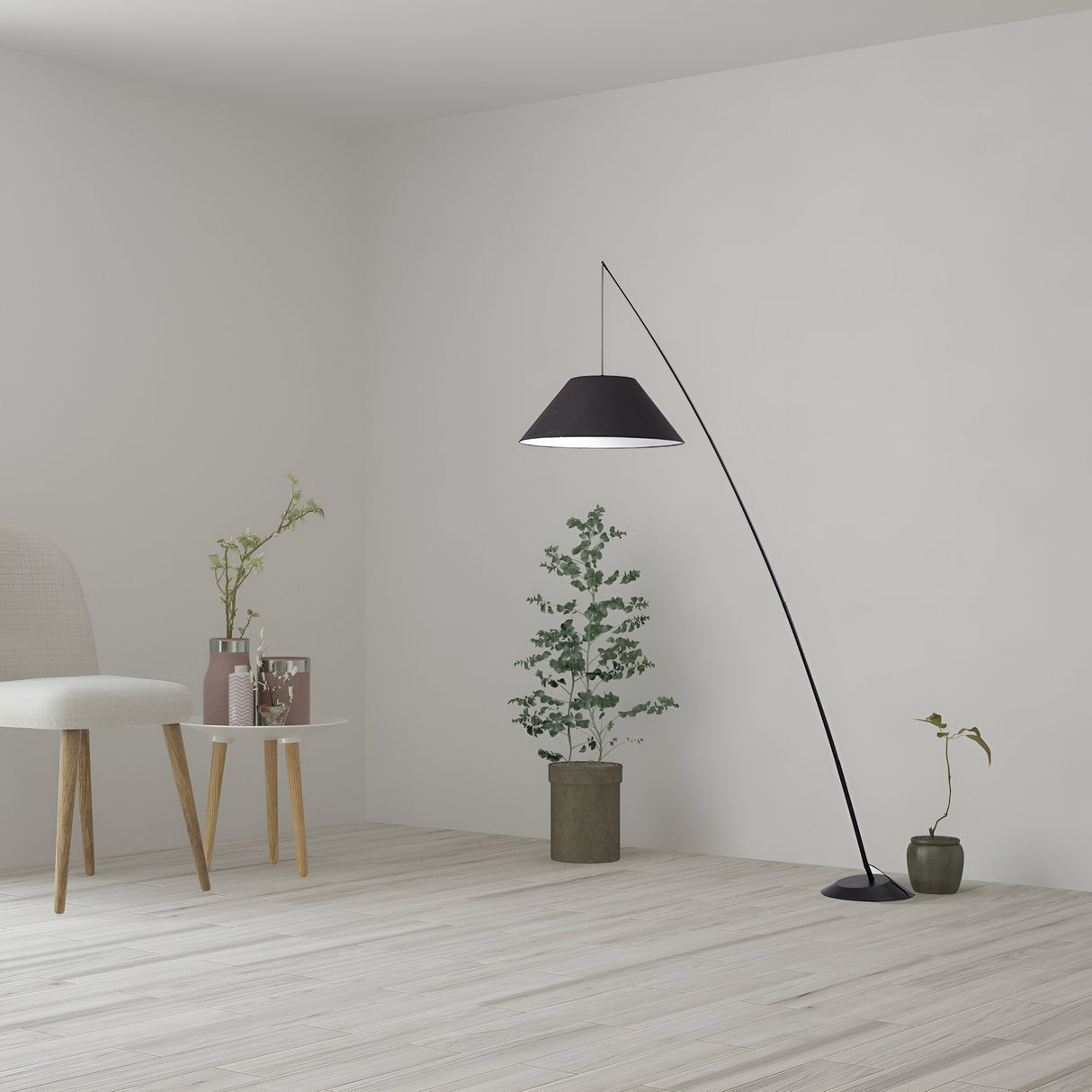 A minimalist room features a light wooden floor, the contemporary Campanula Floor Lamp - Black, and a beige chair accented by plants in simple pots. Plain white walls enhance the serene atmosphere with industrial edge lighting.