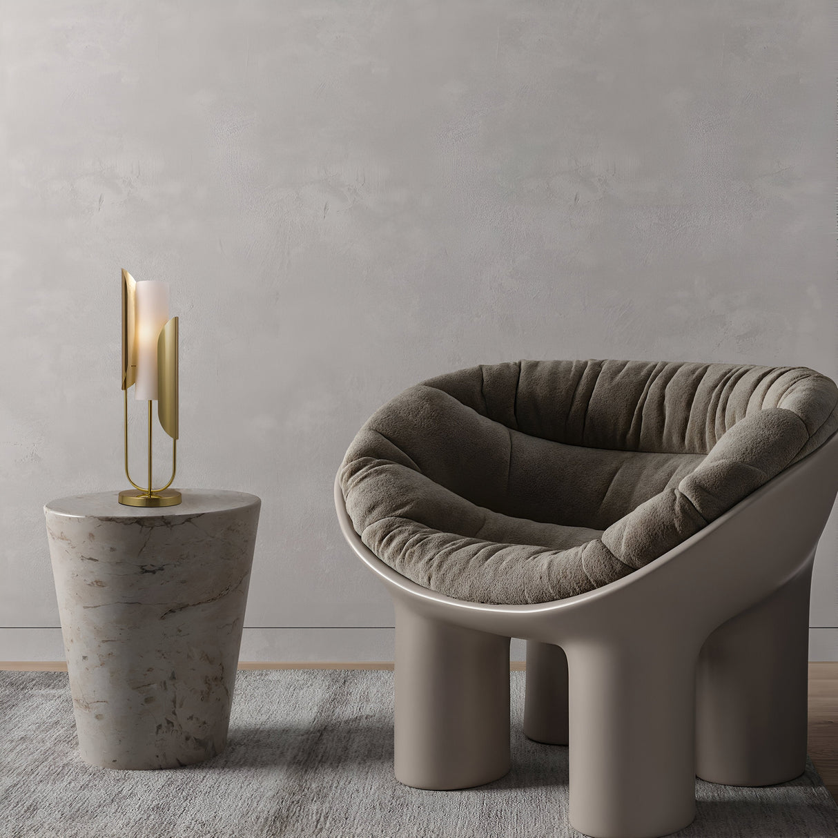 A modern lounge chair with a plush gray cushion complements a small marble side table. On the table sits the Cipresso Table Lamp - Gold With Frosted Glass, enhancing its minimalist and contemporary appeal.