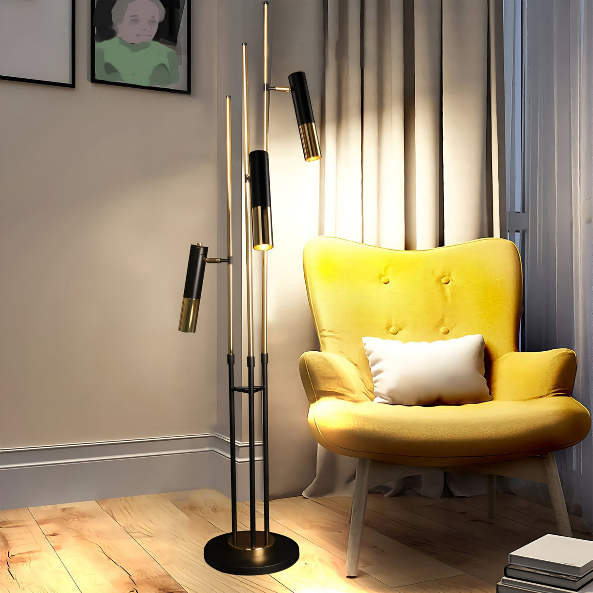 A cozy reading corner with a yellow armchair, white cushion, Leonard 3 LED Floor Lamp in black & gold, beige curtains, light wood floor, and a framed portrait. The warm lighting creates a relaxing atmosphere.