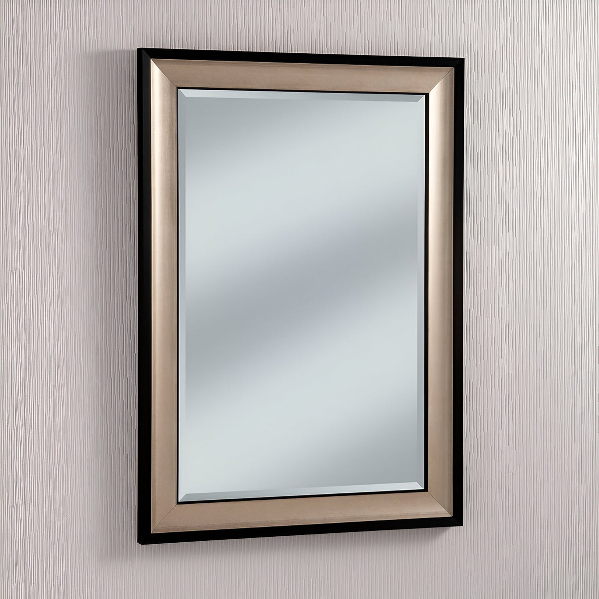 The Liberty Rectangle Wall Mirror - Champagne, with its sleek champagne-colored frame, graces a lightly textured wall. It reflects a softly blurred image that adds elegance and luxury to the room's decor.