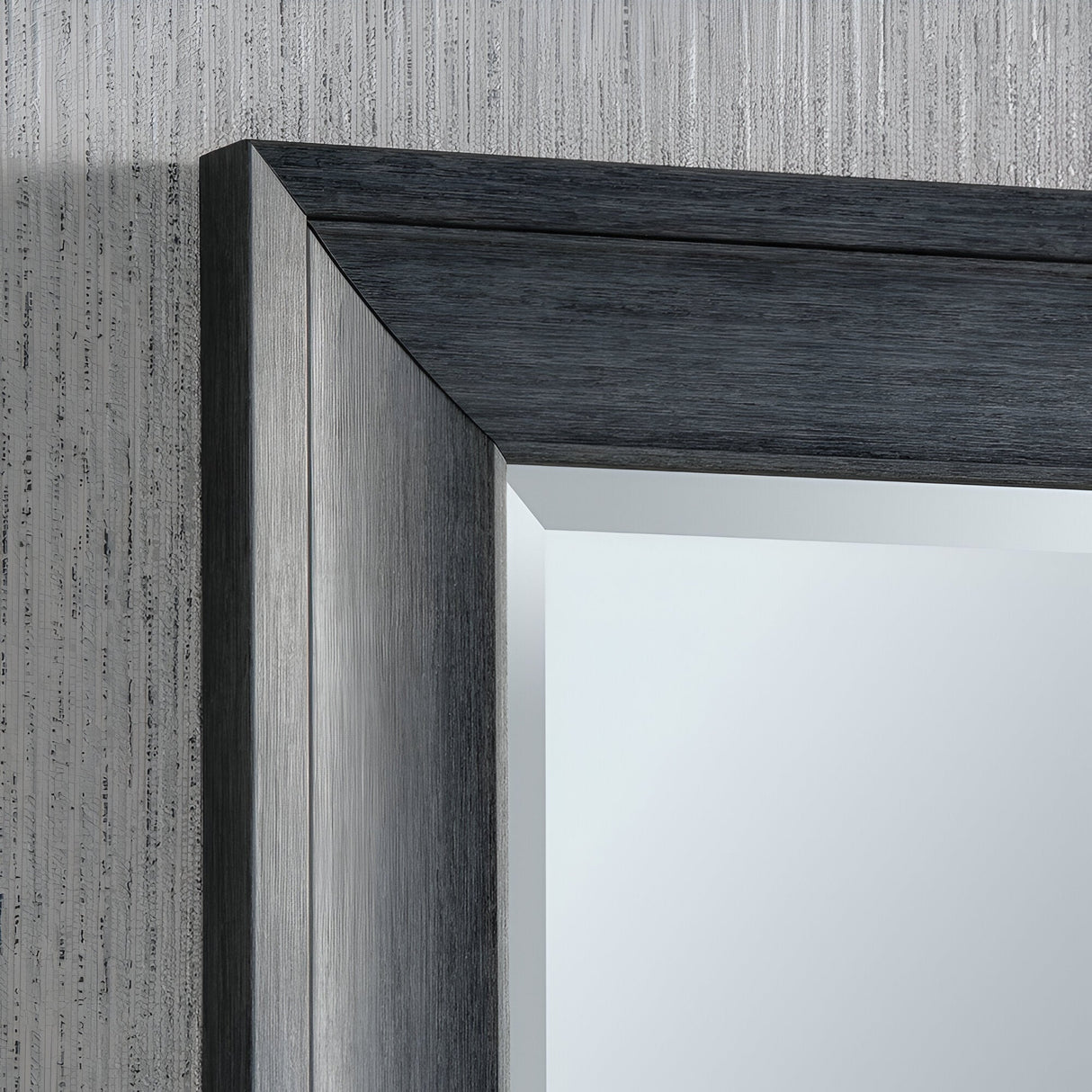 Get a closer look at the Liberty Rectangle Wall Mirror - Dark Grey, showcasing its dark grey frame with a metallic texture and angled edges. The textured wallpaper in neutral tones elevates the mirror's sleek and contemporary design, exuding modern sophistication.