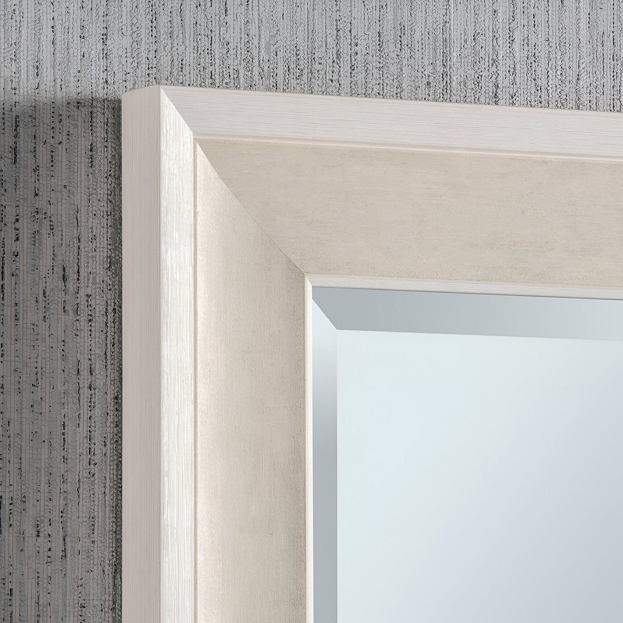 Close-up of the Liberty Rectangle Wall Mirror - White, showcasing a contemporary design with a pale wooden frame. It is mounted on a textured gray wall, and the beveled edge of the frame adds an understated decorative touch to its minimalist aesthetic.