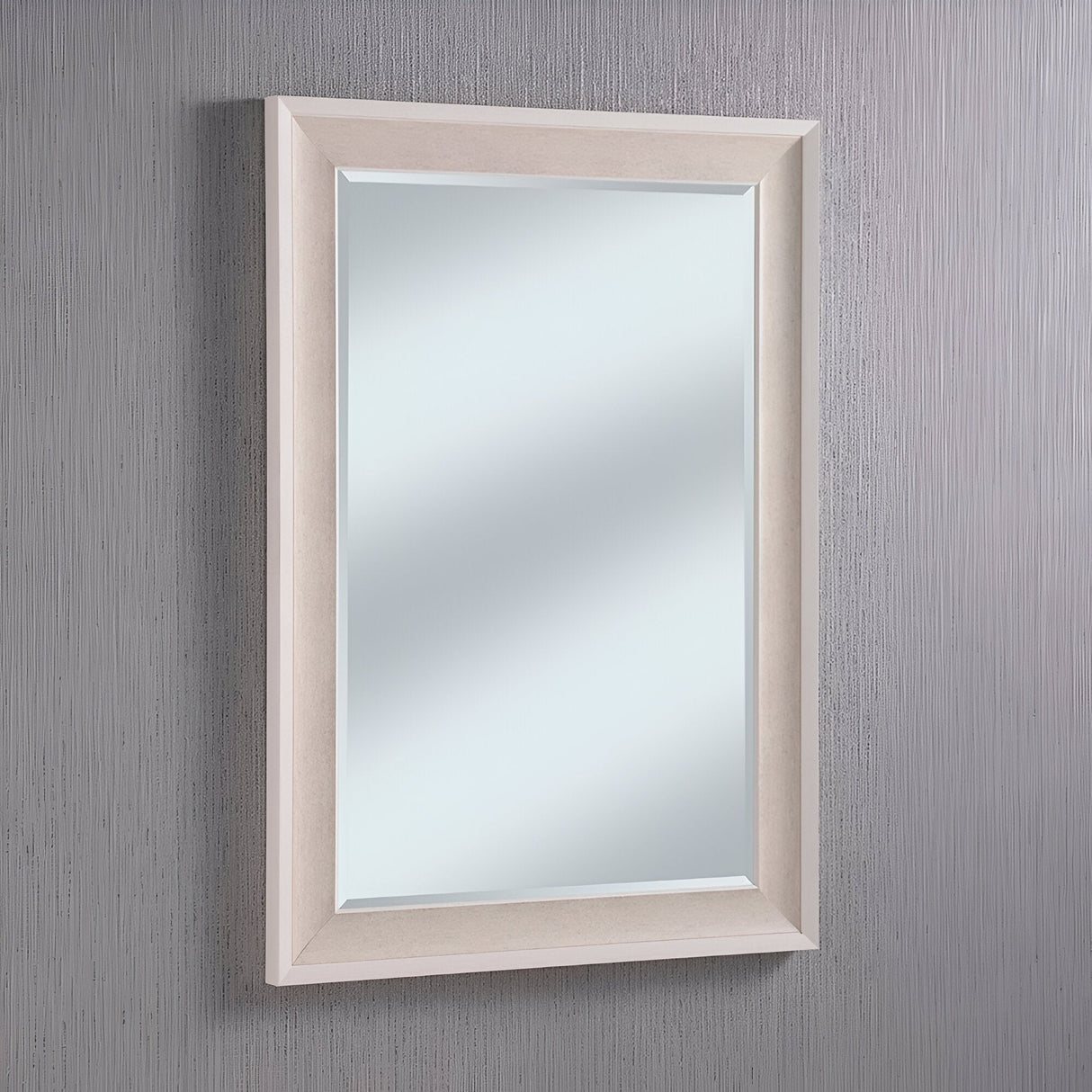The Liberty Rectangle Wall Mirror in white is mounted on a textured gray wall. The mirror reflects light beautifully, and its simple design offers a modern look that enhances any space.