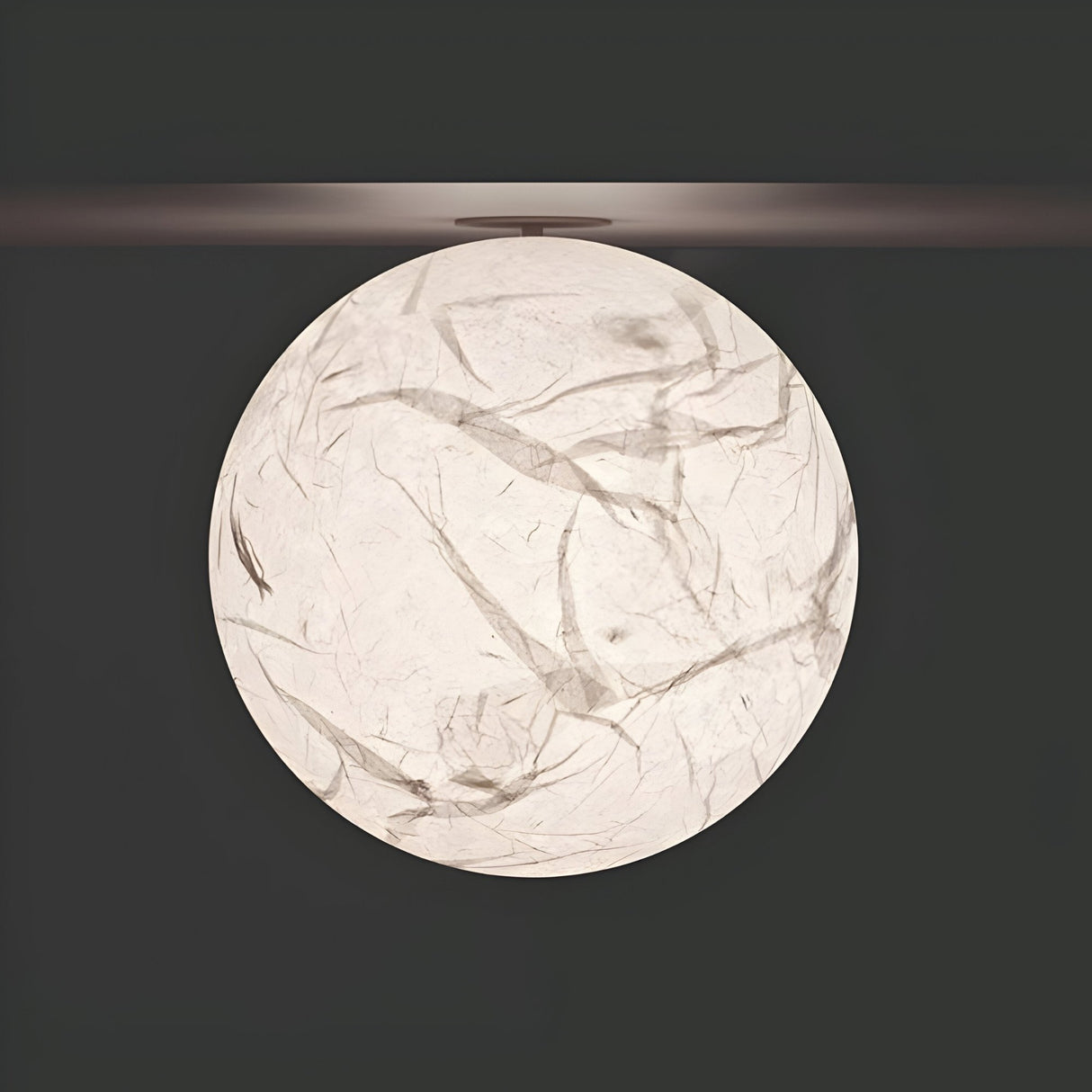 The Lunar Ceiling Light - White features a round design with marbled texture, adding celestial elegance and casting a soft glow against dark backgrounds.