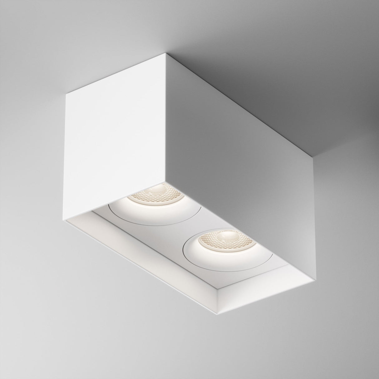The Slim Twin Rectangular Surface Downlight - White features two recessed LED lights in a sleek rectangular form, ideal for a modern interior and offering contemporary style when mounted on any ceiling.