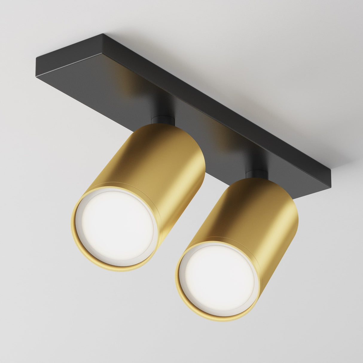 The Focus S Twin Bar Spotlight in black and matte gold features two cylindrical spotlights on a rectangular base, mounted against a white ceiling. This modern design provides adjustable lighting with the dual lights positioned side by side and facing downward.