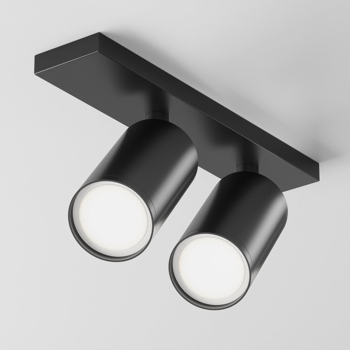 The Focus S Twin Bar Spotlight in black is a ceiling-mounted fixture featuring two adjustable downward lights, enhancing modern interiors with its sleek design against a white surface.