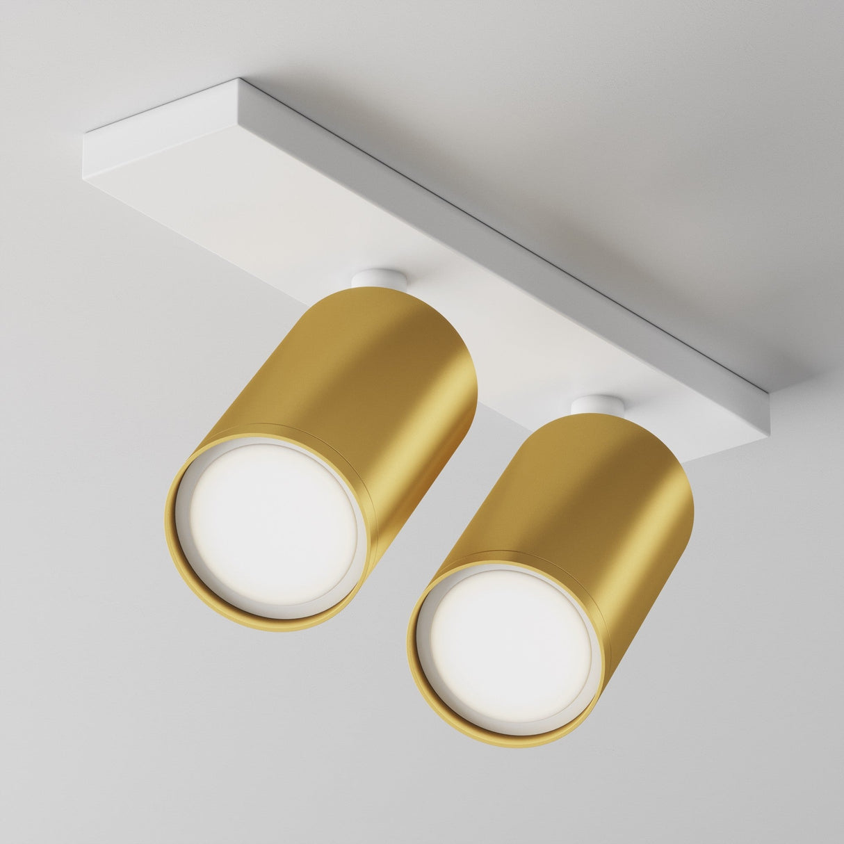The Focus S Twin Bar Spotlight features two adjustable spotlights in matte gold on a white rectangular base, ideal for contemporary interiors with its sleek and luxurious downward lighting.