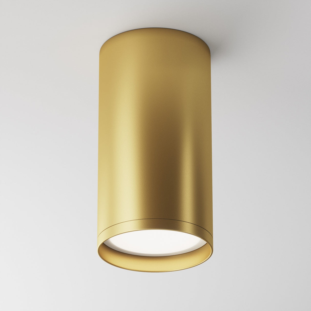 The Focus S Fixed Round Surface Mounted Downlight in matte gold is a modern cylindrical fixture installed on a white ceiling, providing focused directional lighting downward.