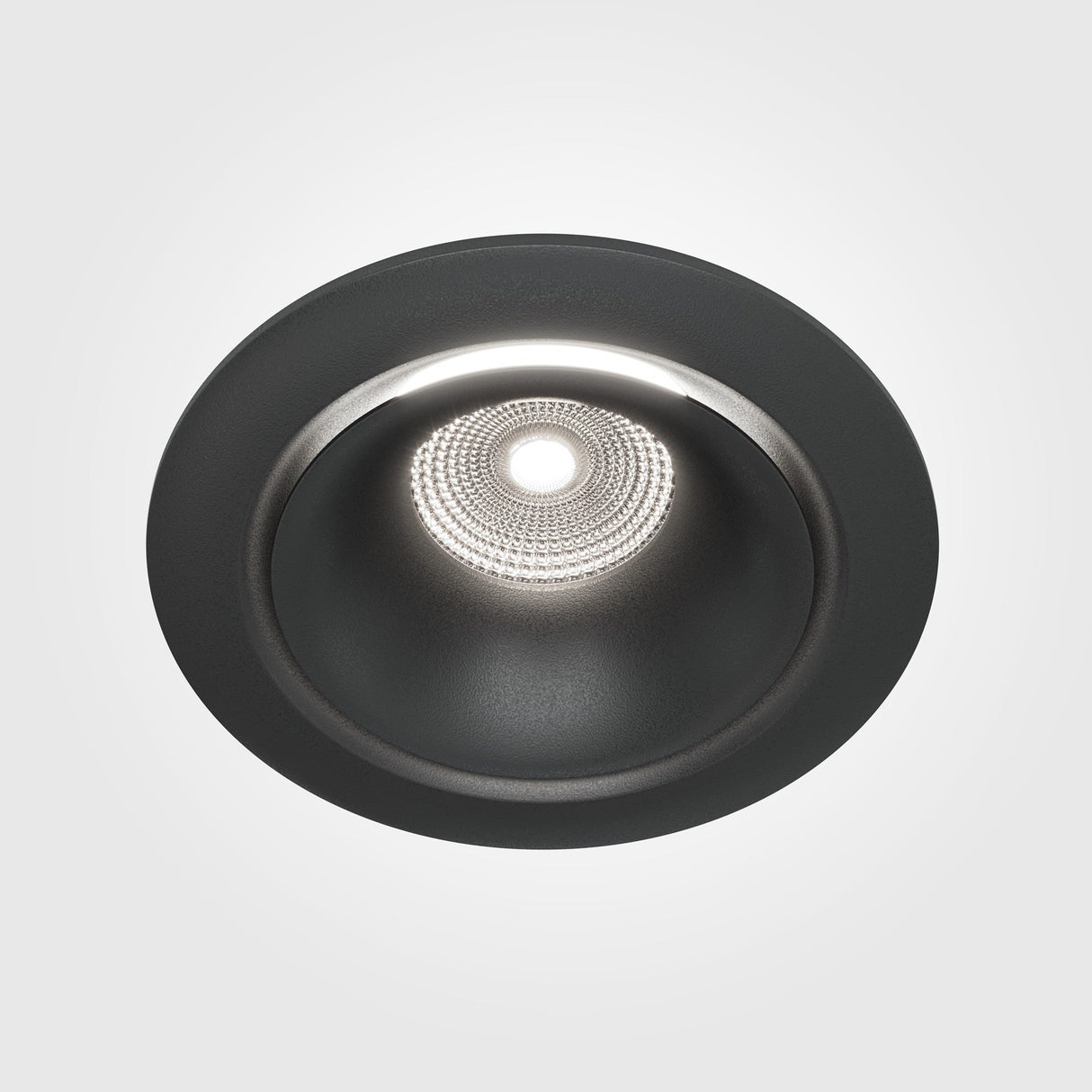 The Yin LED Dimmable Round Recessed Downlight in black features a sleek aluminum frame, a modern circular design, and emits bright 4000K light from its central LED, set against a plain, light-colored background with a textured reflective surface.