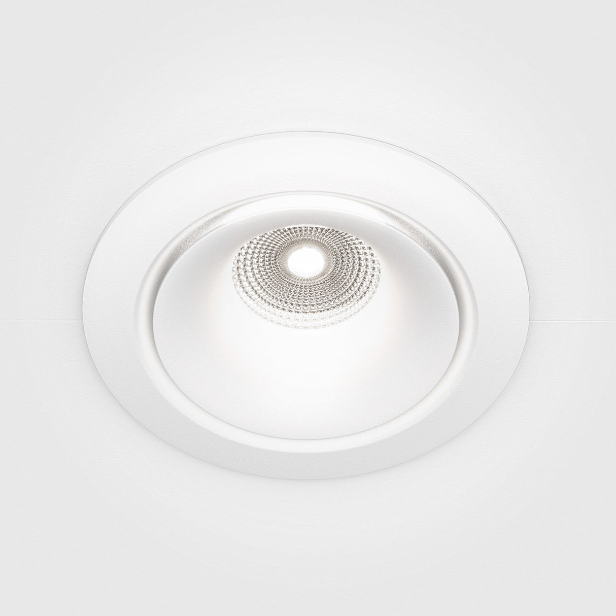 The Yin LED Dimmable Round Recessed Downlight 12W 4000K - White features a sleek design with a circular shape and white trim. Its textured, metallic interior creates intricate light patterns on a smooth white ceiling, offering adjustable brightness to suit any ambiance.