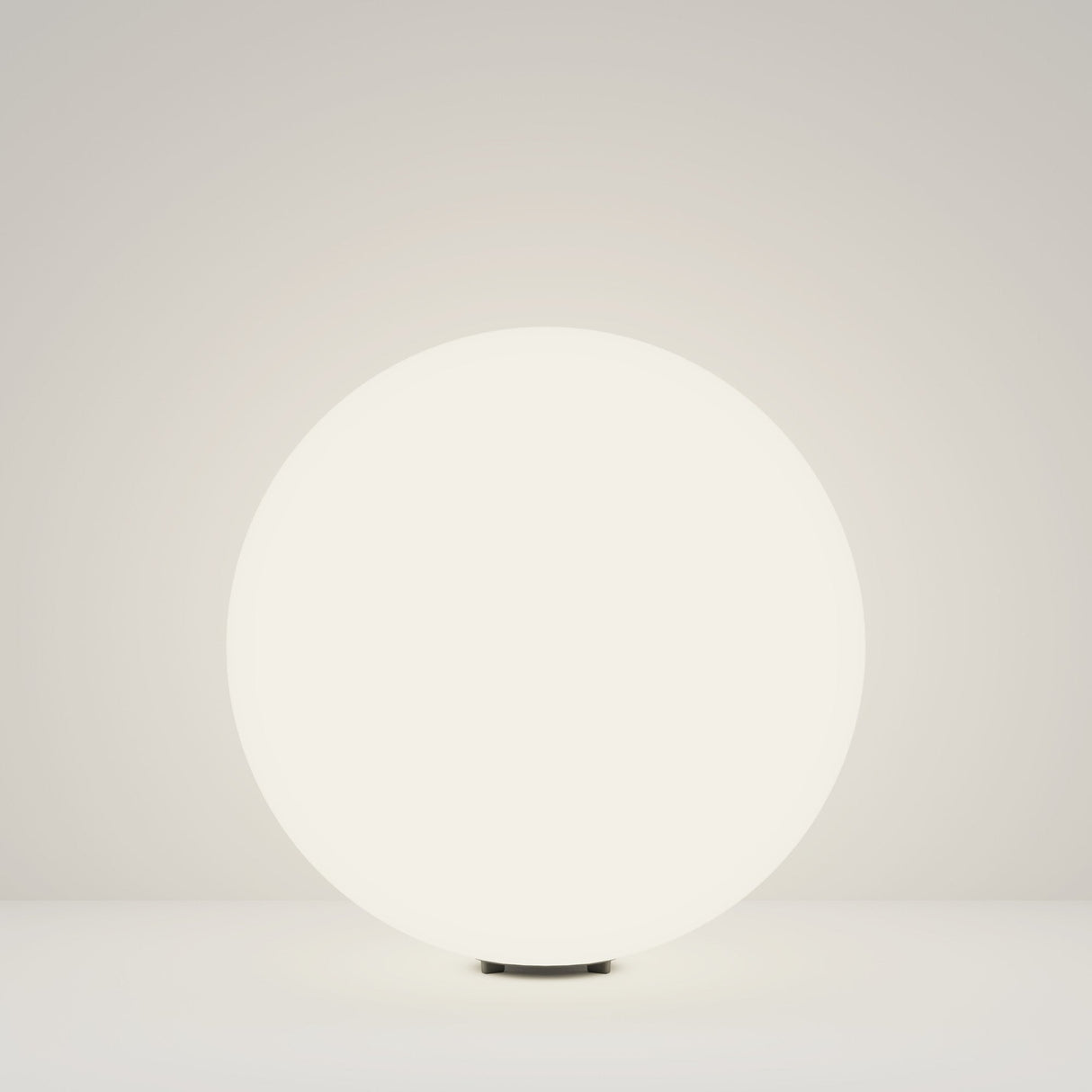 The 49cm Erda Pedestal Light in white, with its modern design and illuminated round form, emits a soft glow on a plain surface, enhancing outdoor lighting with understated charm.