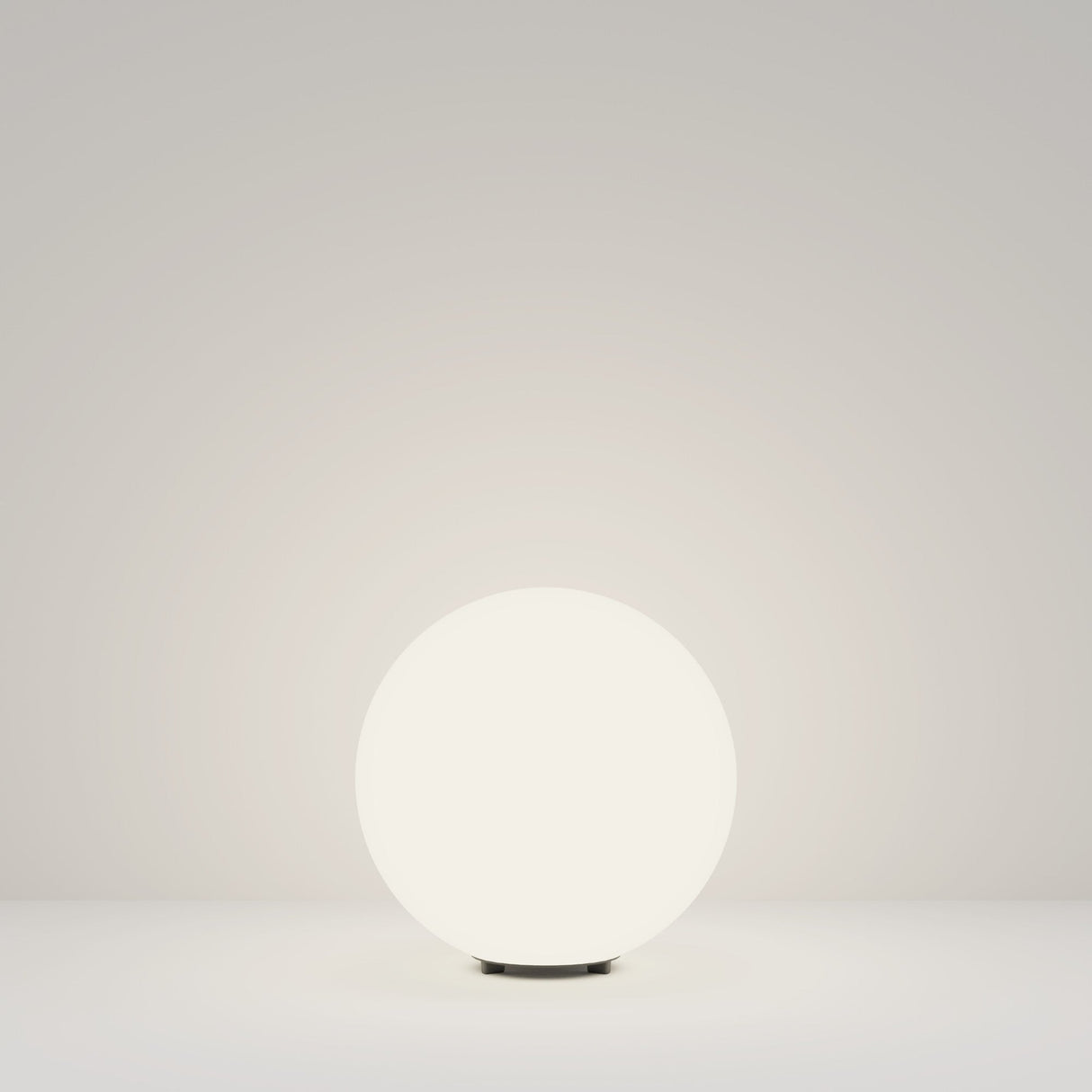 The Erda Pedestal Light 29cm - White casts a gentle glow on a plain, light surface against a matching background. Its weather-resistant design is ideal for fostering a minimalist and serene ambiance in both indoor and outdoor settings.