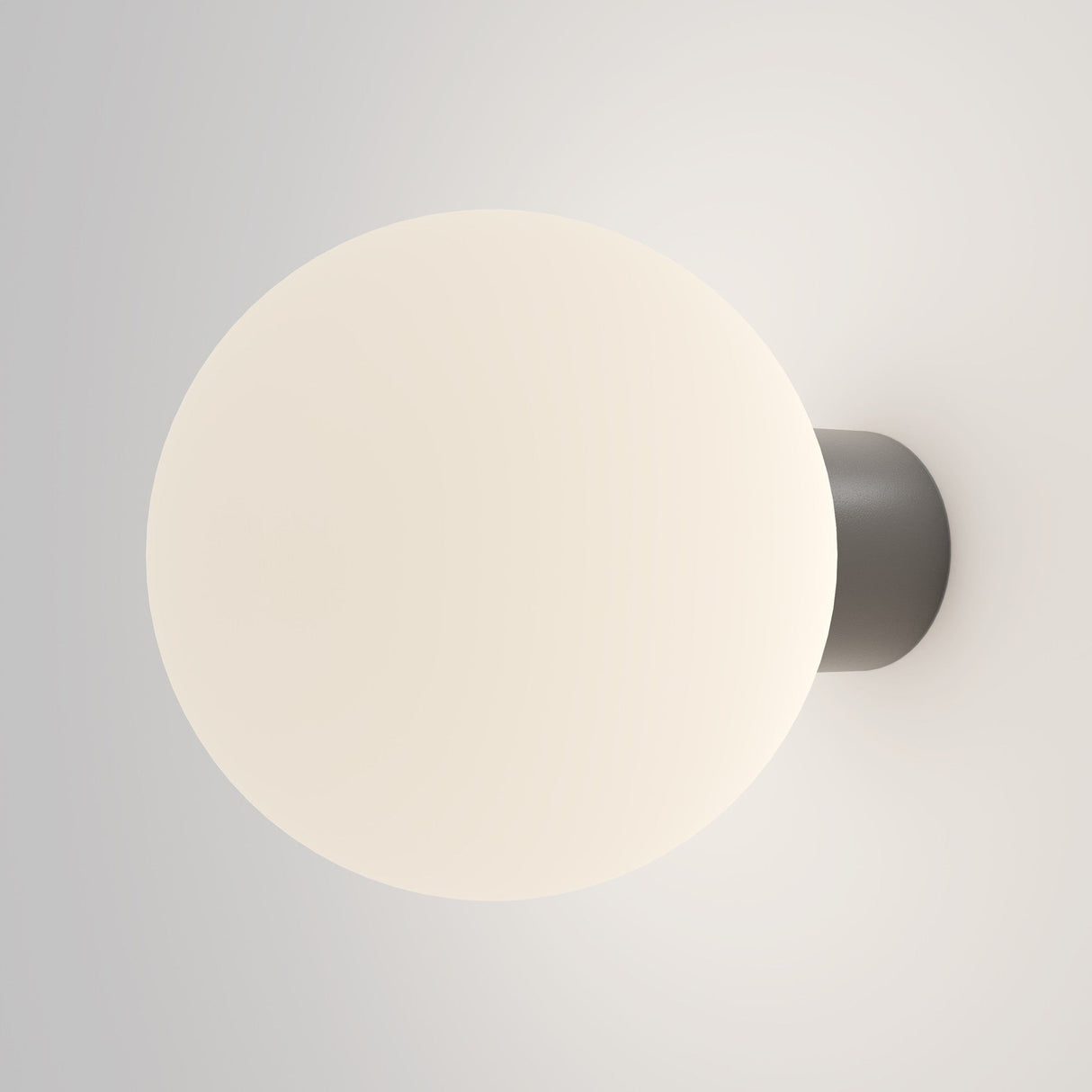 The Bold Outdoor Wall Light - Grey (O598WL-01GR1) features a spherical frosted white glass shade on a dark circular base, providing a soft, warm glow. Its IP65 rating ensures it is both stylish and weather-resistant, making it an ideal wall sconce for enhancing outdoor spaces.
