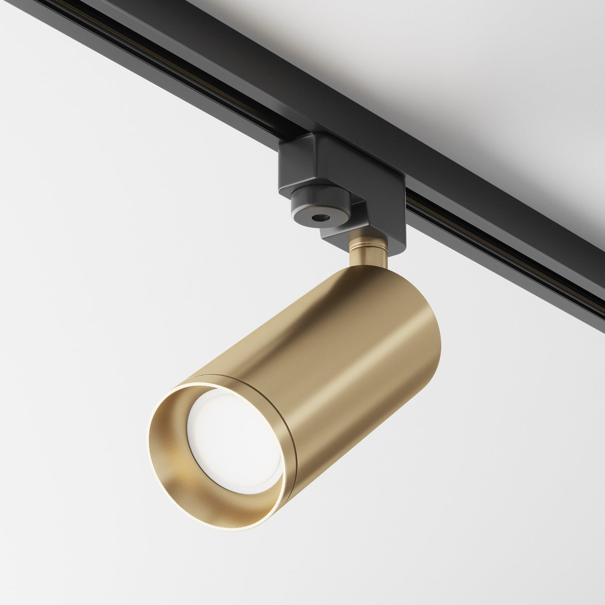 A Focus Single Phase Unity Track Spotlight in matte gold is mounted on a black rail against a white ceiling, featuring GU10 compatibility for sleek, modern directional lighting.