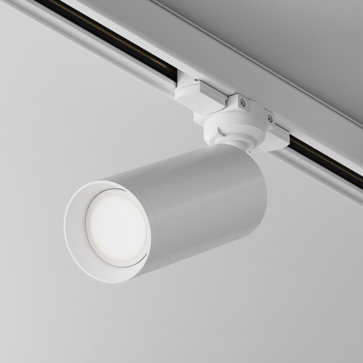The Focus 3-Circuit Trinity Track Spotlight features a sleek, cylindrical design on a metal track. Its adjustable, downward lighting complements its modern look against a gray ceiling and ensures optimal illumination with GU10 base compatibility.