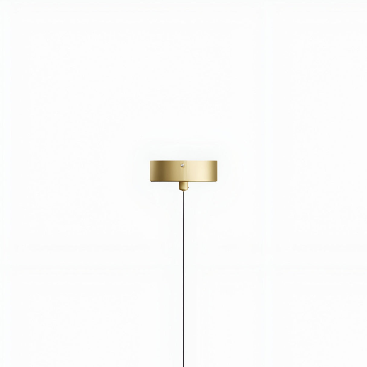 The Micro LED Pendant Light - Gold features a minimalist gold finish with a round, flat shade mounted on a white wall. A single thin black cord hangs straight down, accentuating its modern design.