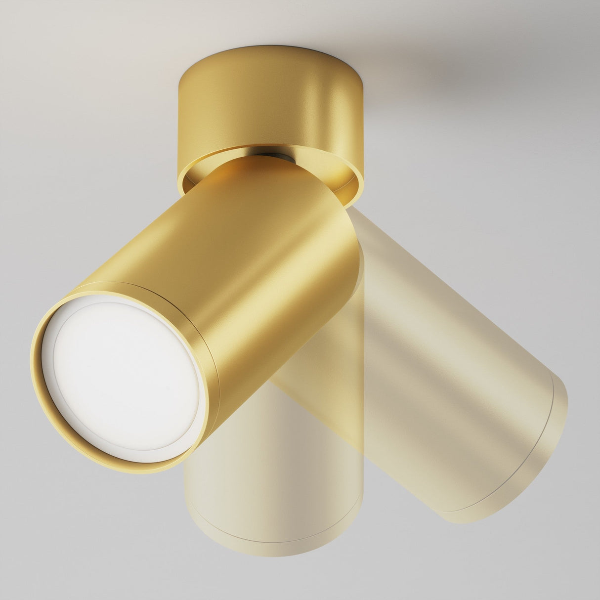 The Focus S Single Surface-Mounted Spotlight - Matte Gold boasts a modern design with two adjustable heads in opposite directions on a round base, casting a soft glow on white ceilings—ideal for contemporary interiors.