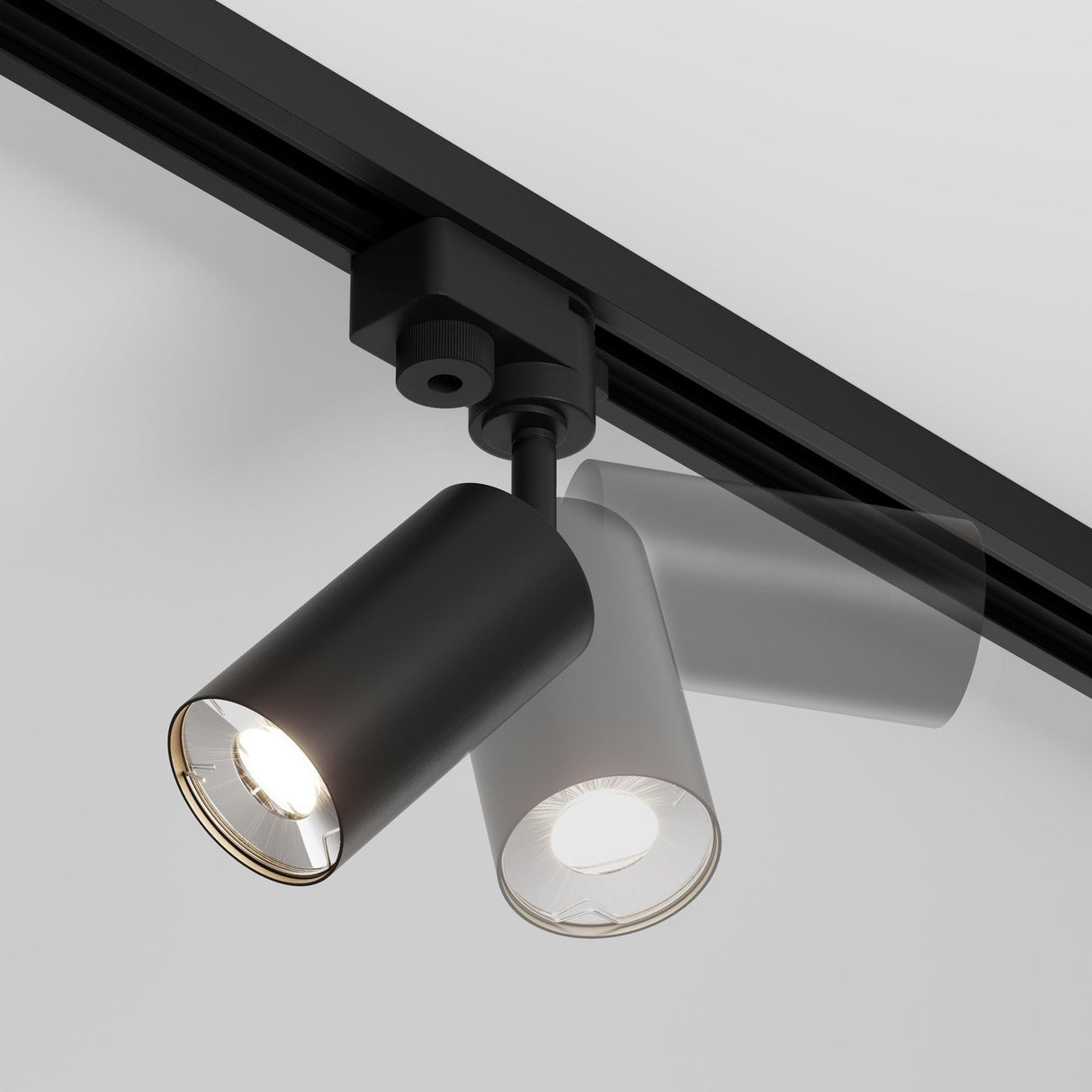 The Focus Mini Single Phase Unity Track Spotlight - Black features a sleek cylindrical design, ideal for modern industrial interiors. Ceiling-mounted, it provides versatile motion with a solid fixture and semitransparent overlay for new positioning, and is activated when turned on.