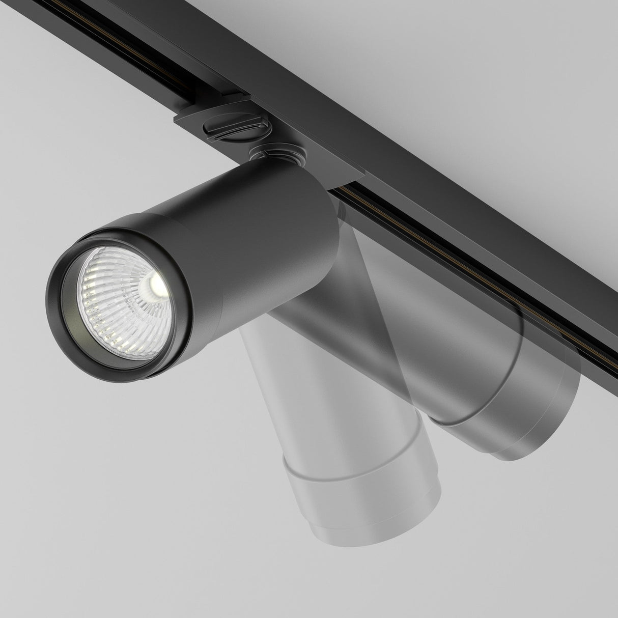 Close-up of the Focus Zoom LED Dimmable Single Phase Unity Track Spotlight 12W 4000K in black, mounted on a ceiling. The modern cylindrical light is angled downward, emitting bright white low-glare lighting. Both the fixture and ceiling boast a sleek, minimalist design.