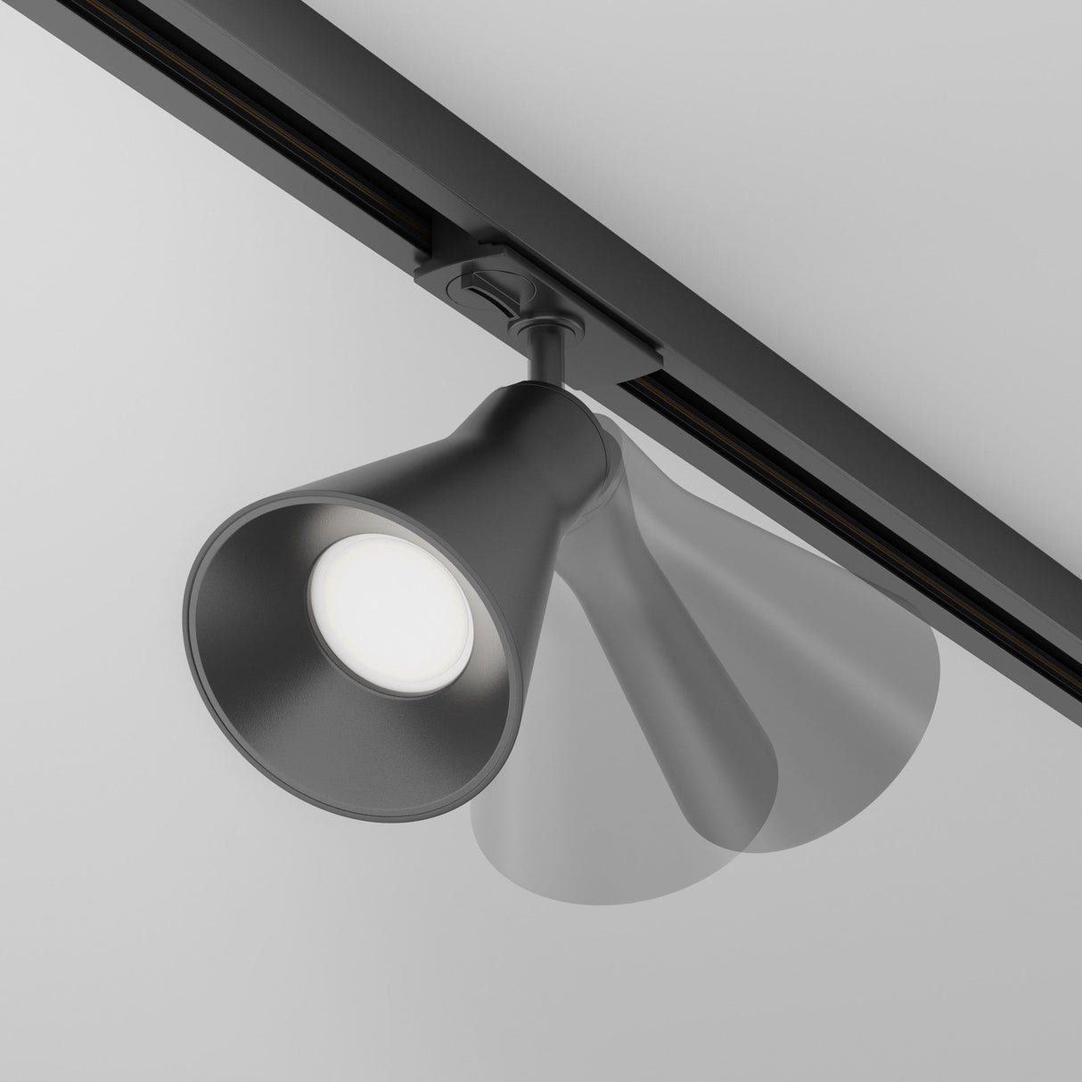 The Virar Single Phase Unity Track Spotlight in black, with energy-efficient LED bulbs, is ceiling-mounted and displayed dynamically to show its motion range. It emits bright white light, accentuating its sleek, modern design.