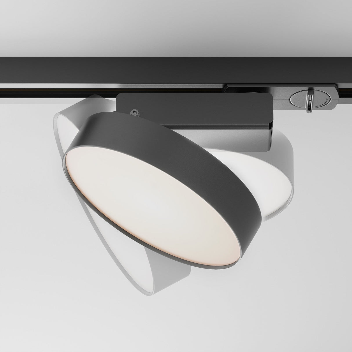 The Zon LED Single Phase Unity Track Spotlight 12W 3000K in black is a modern, minimalist ceiling light fixture with a sleek black frame and circular white interior, perfect for illuminating interiors elegantly when attached to a narrow track system on a white ceiling.