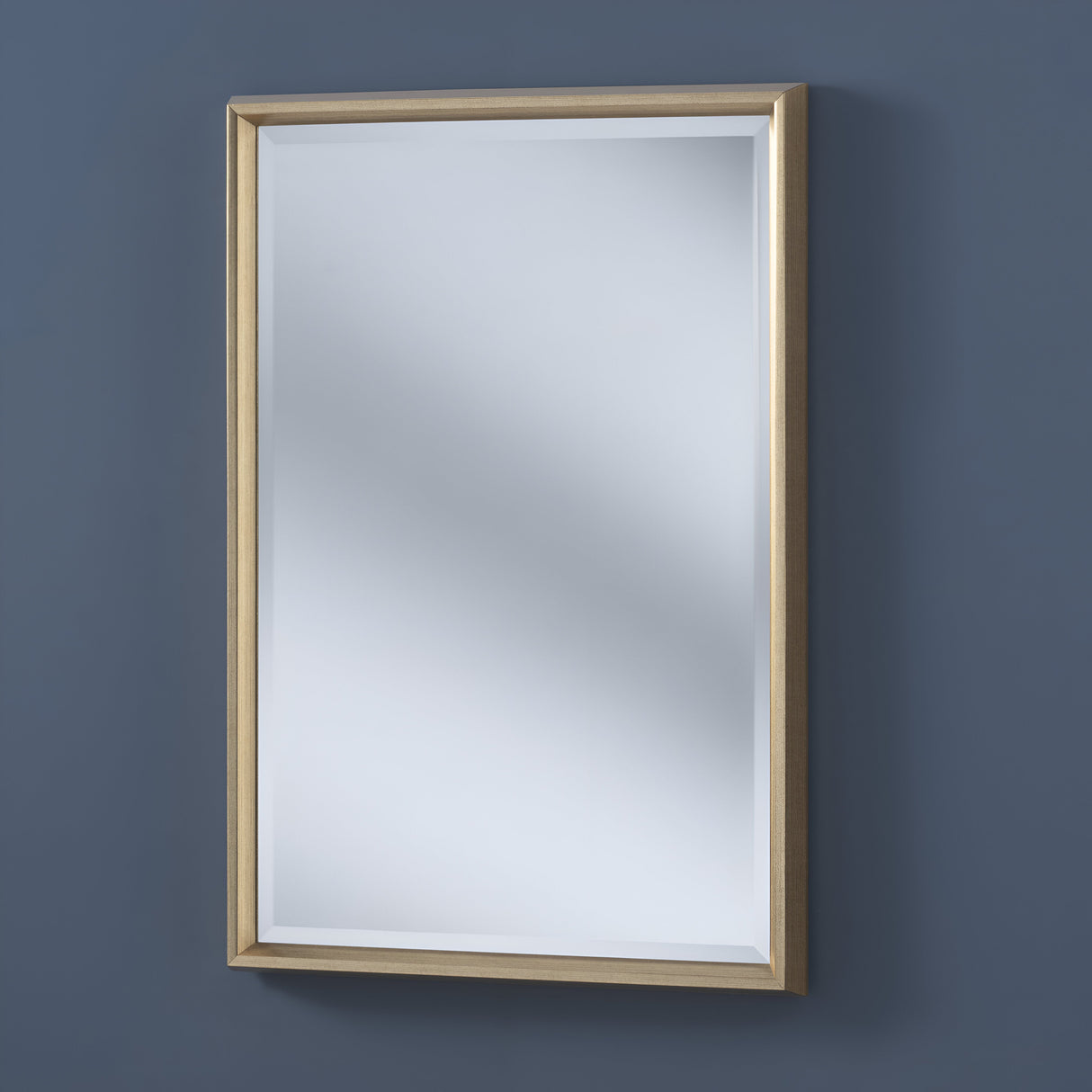 The Lirion Rectangle Wall Mirror - Gold elegantly hangs on a blue wall with its vertical rectangle shape, subtly reflecting light and enhancing the spaces charm.