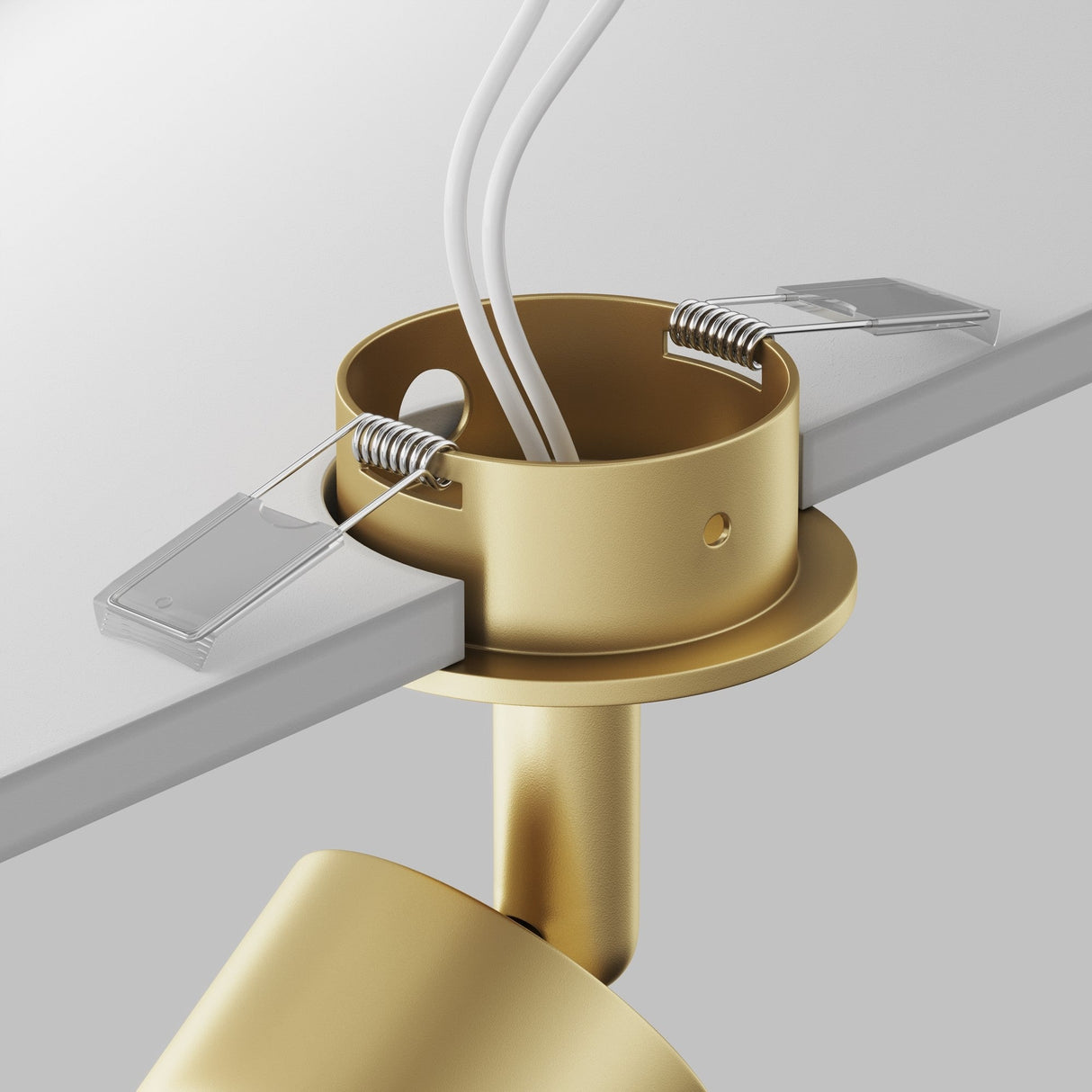 Close-up of the Focus Single Recessed Spotlight in matte gold. Wires emerge from the top, and its swivel mechanism is slightly inserted into a white surface with metal clips for secure positioning.