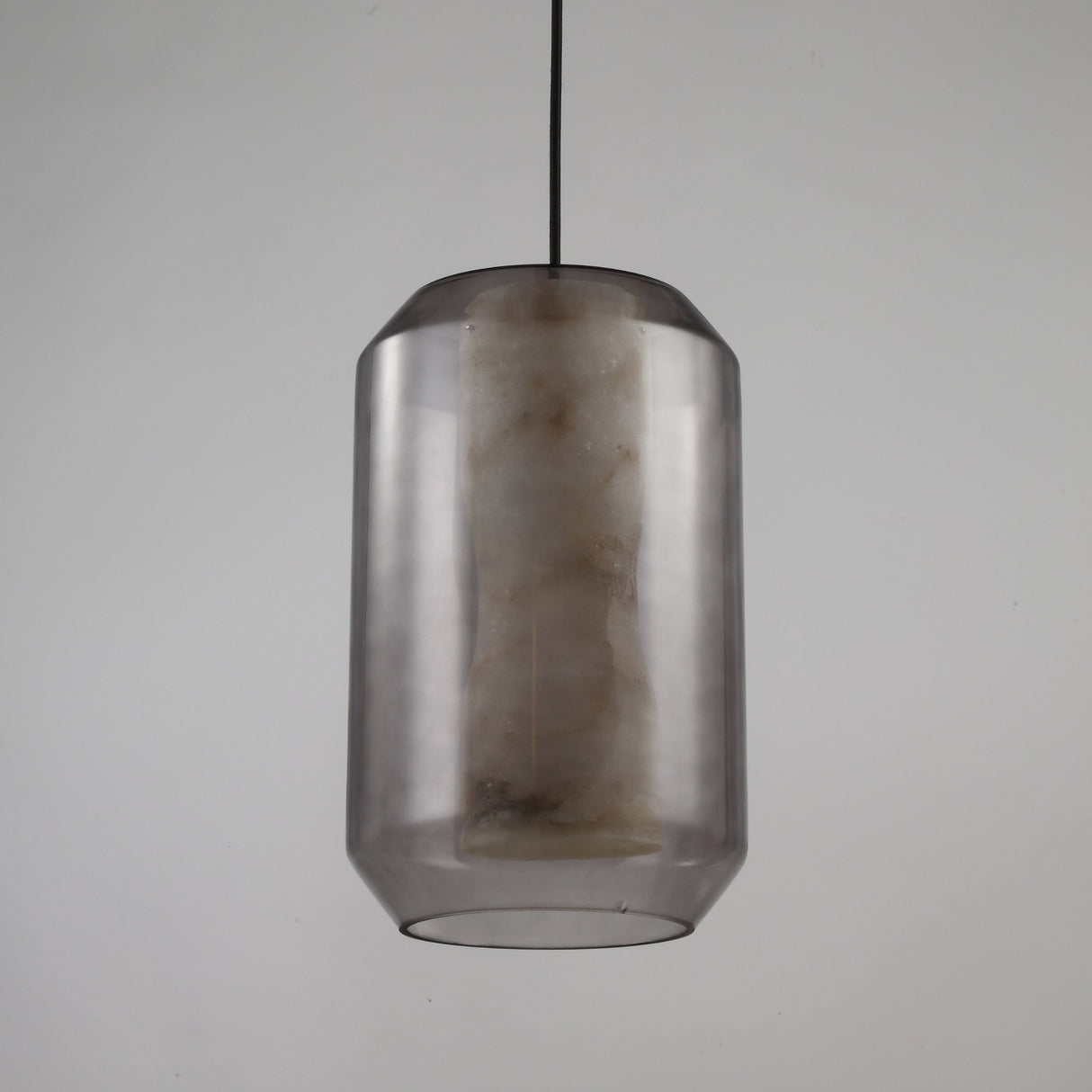 Niori Vale faceted pendant light with a natural Spanish alabaster core inside a smoked glass lantern shade on a black flex, shown on a light background.