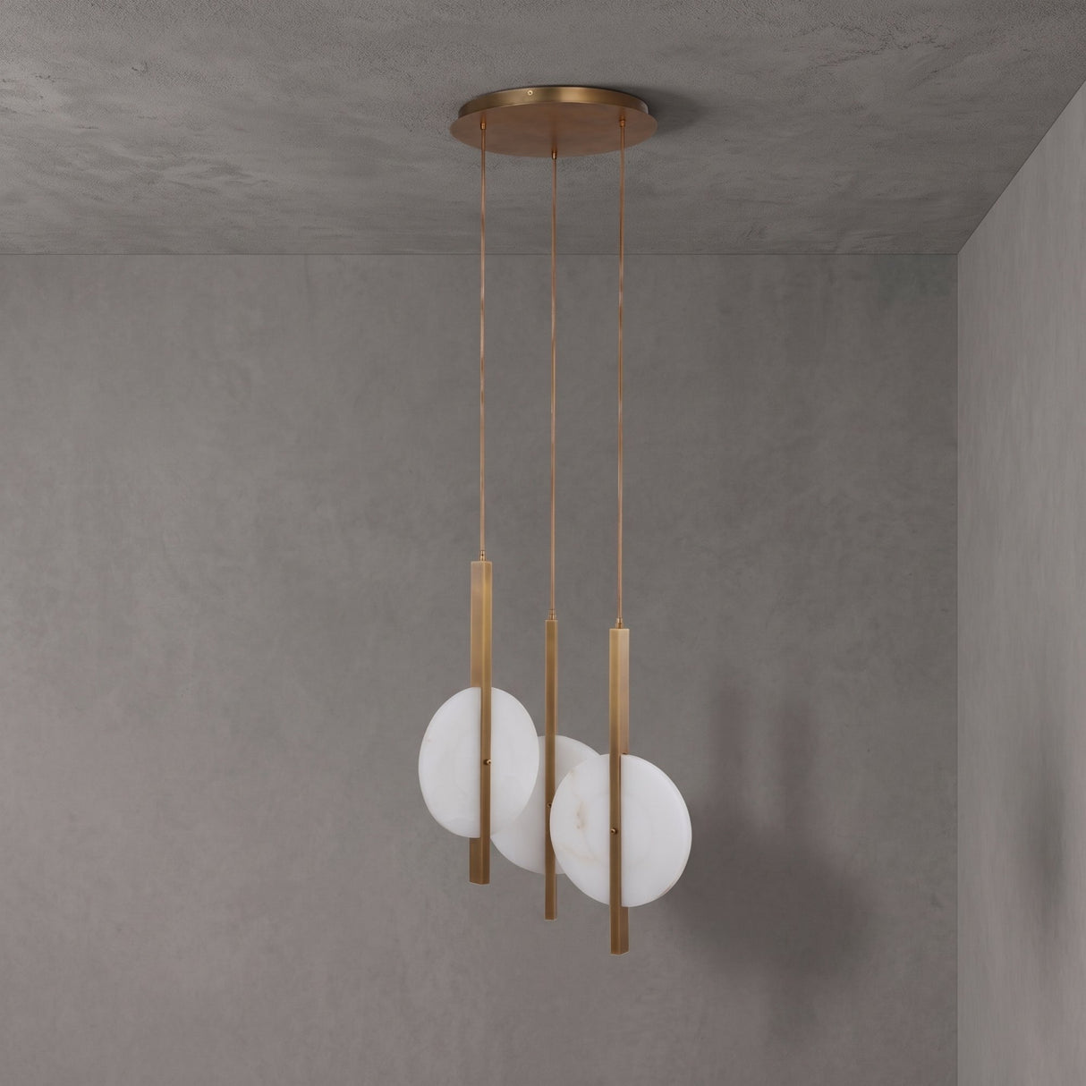 Niori Elyra 3 Light LED Alabaster Cluster Chandelier in brushed brass with staggered flat oval alabaster discs on blade stems, mounted to a grey ceiling.