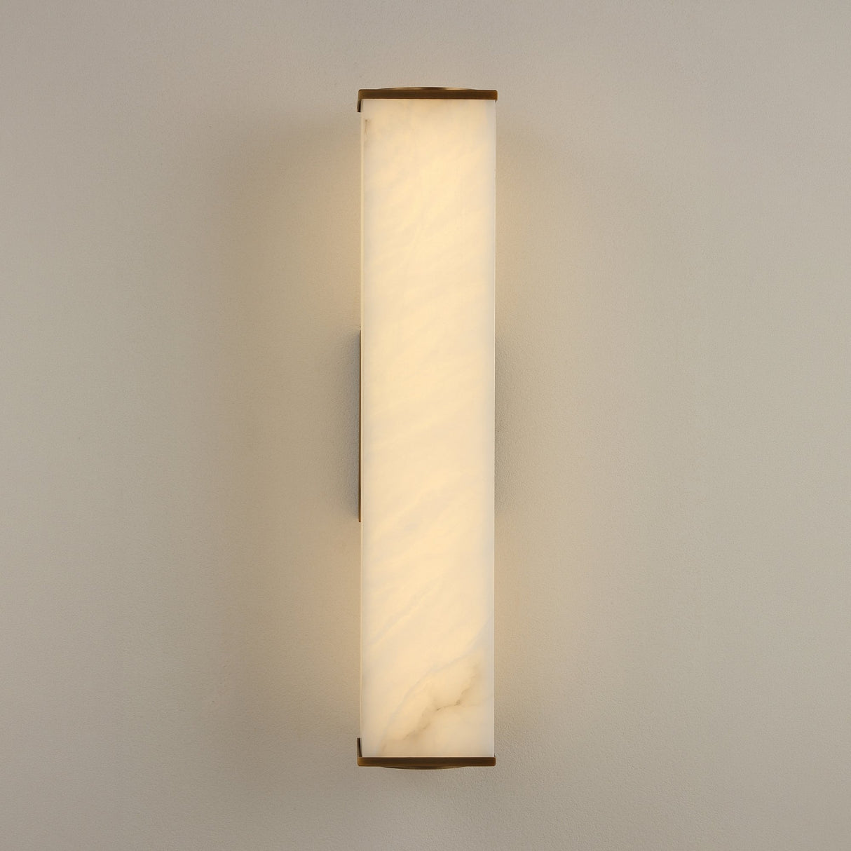 Valmere LED Small Linear Alabaster Wall Light in soft white, a rectangular alabaster panel with brass end caps glowing warm white, shown on a plain light wall.