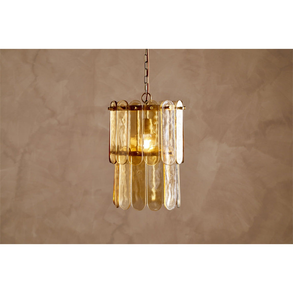 Itan Tiered Recycled Glass Pendant Light in Amber, featuring overlapping flat glass paddles on two brass rings suspended from a chain, shown lit against a neutral background.