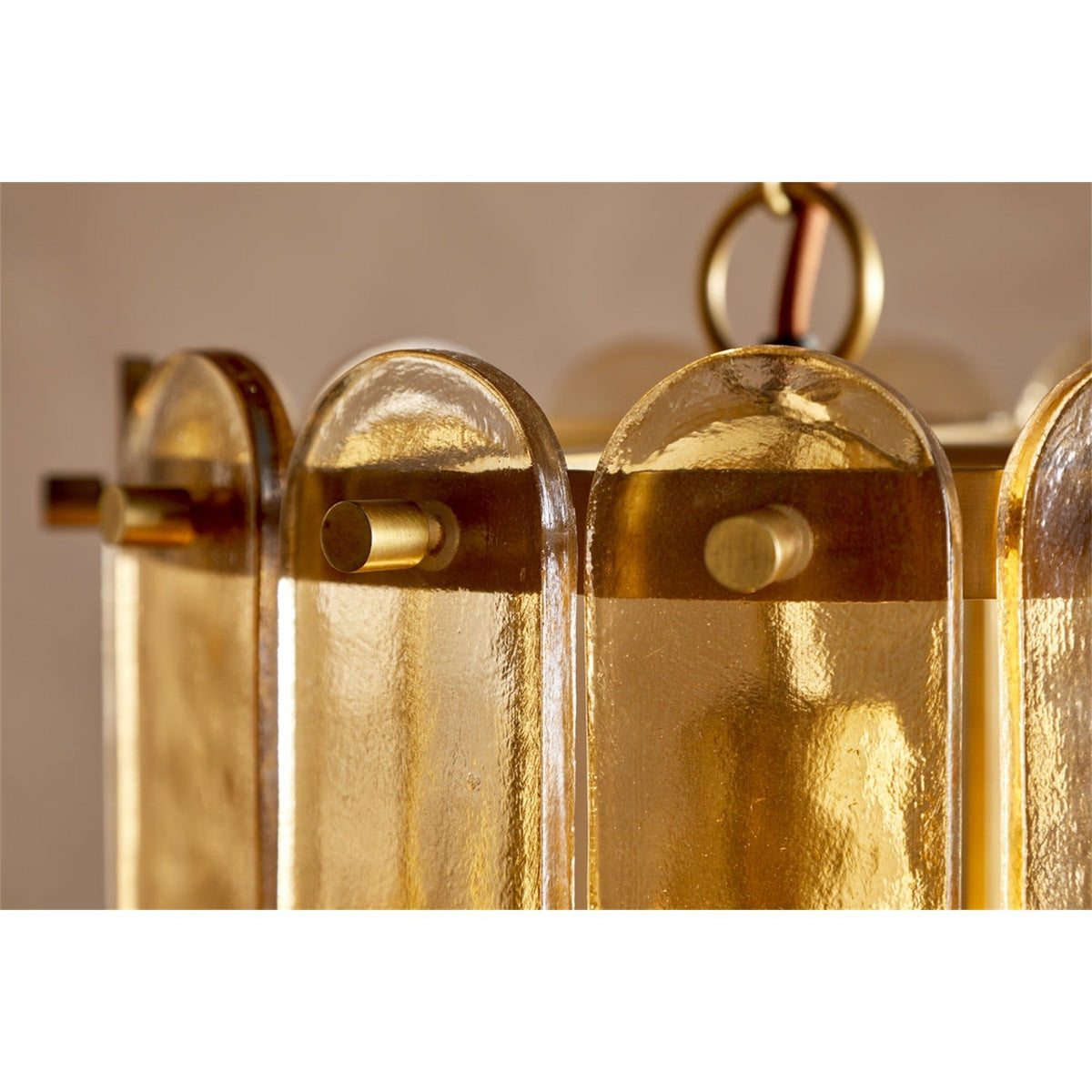Close-up of the Itan Tiered Recycled Glass Pendant Light in amber, showing rounded glass paddles pinned with brass pins to brass rings, with a braided flex above.
