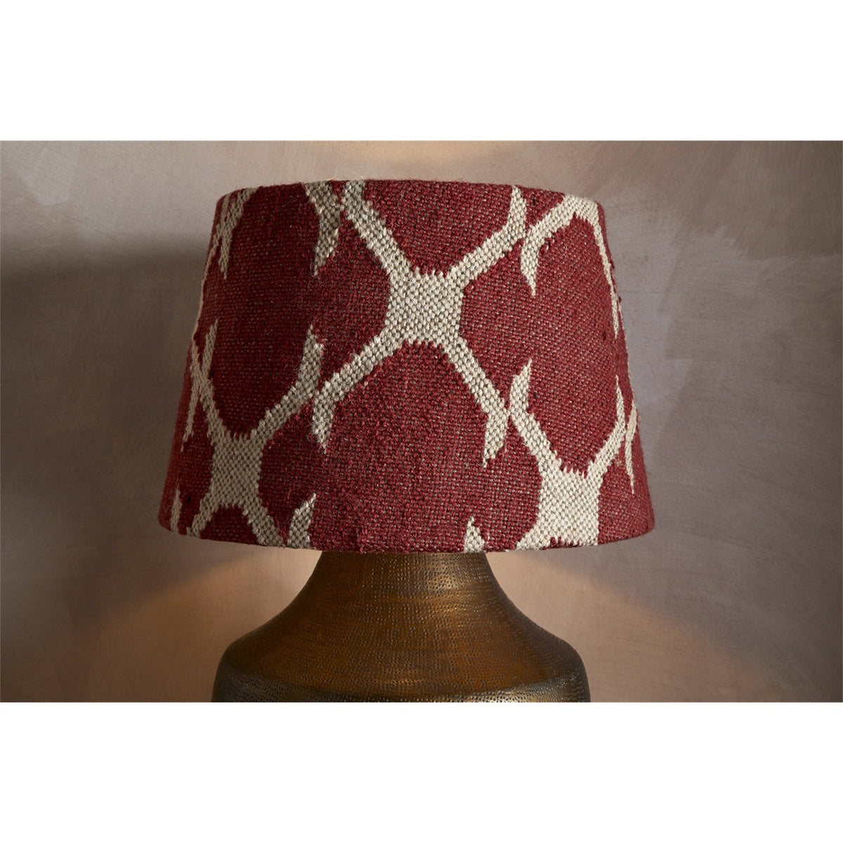Haadu Large Jute Kilim Lampshade in rust and natural, a drum-shaped shade with a woven geometric pattern, shown fitted on a hammered brass lamp base.