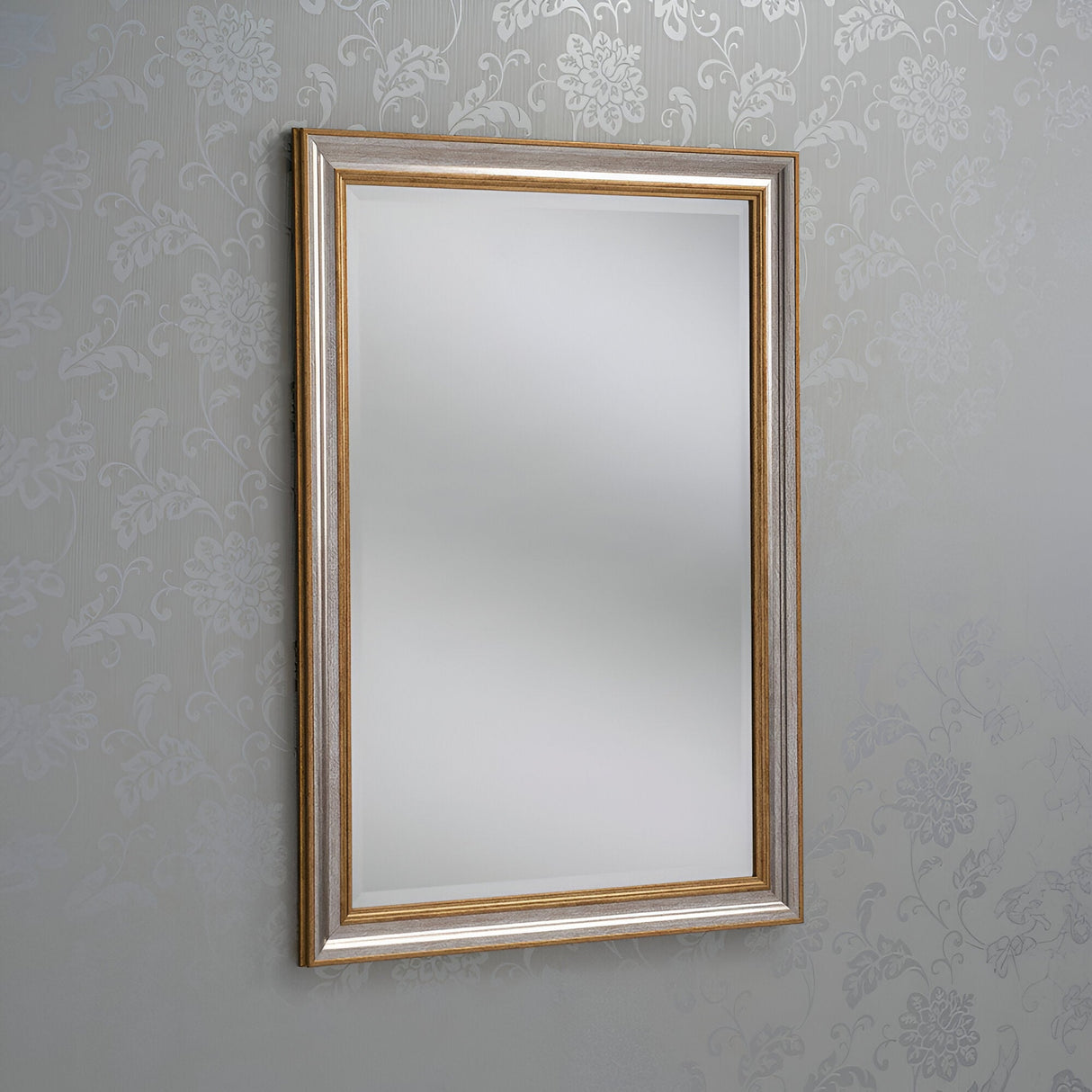 The Napoli Rectangle Wall Mirror - Gold/Silver, featuring a wooden frame, enhances any space with its elegant and classic design. Hanging on a wall adorned with a subtle floral pattern, it reflects light to elevate the home decor.