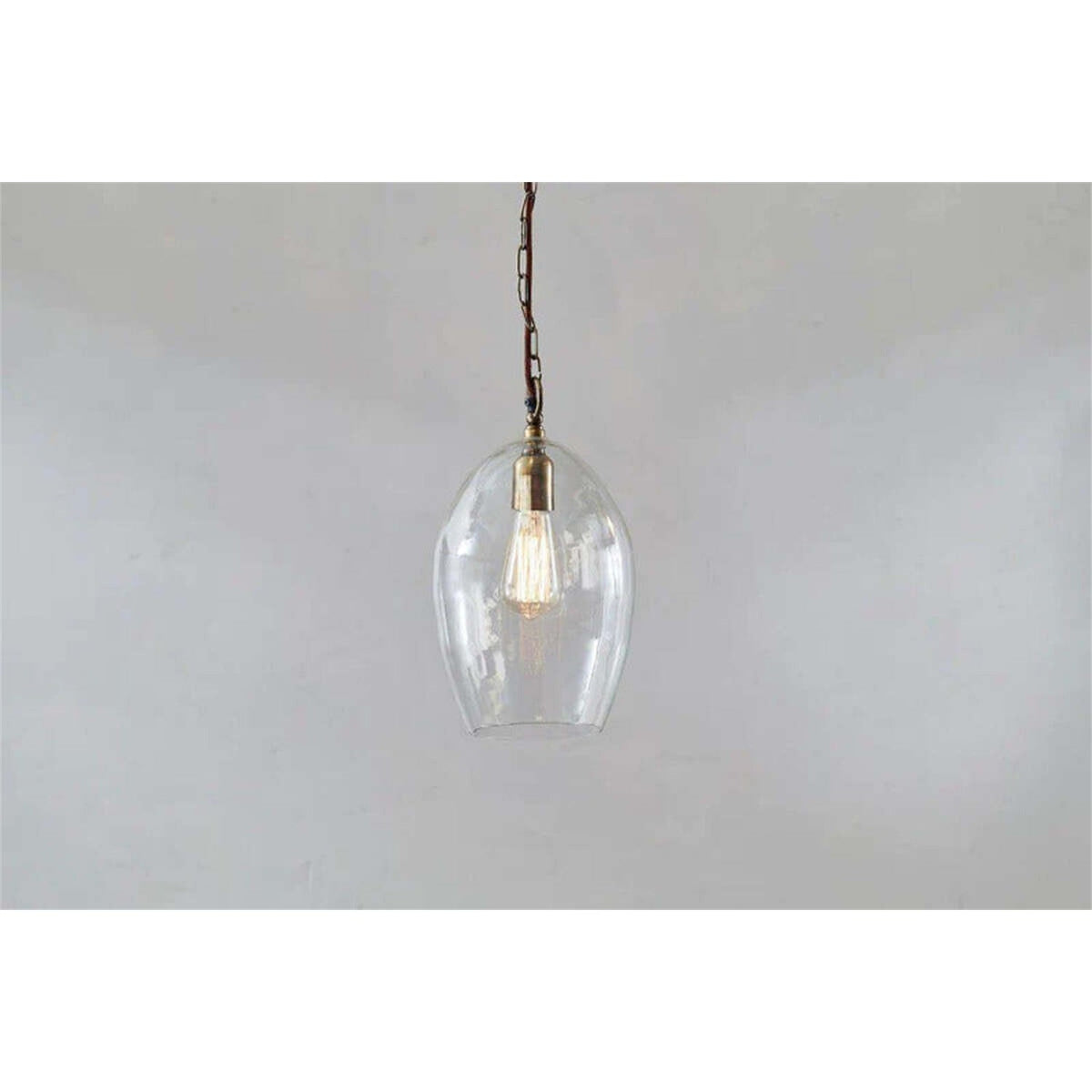Otoro Small Oval Recycled Glass Pendant Light in Clear, egg-shaped glass shade with brass collar and lampholder on a chain, shown against a plain light grey background.