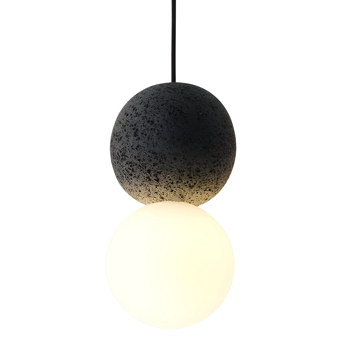 The Origo Concrete Pendant Light - Black & White features two stacked spheres: the top is a dark, textured concrete resembling volcanic rock, while the bottom has an opal glass diffuser that emits a soft white glow.