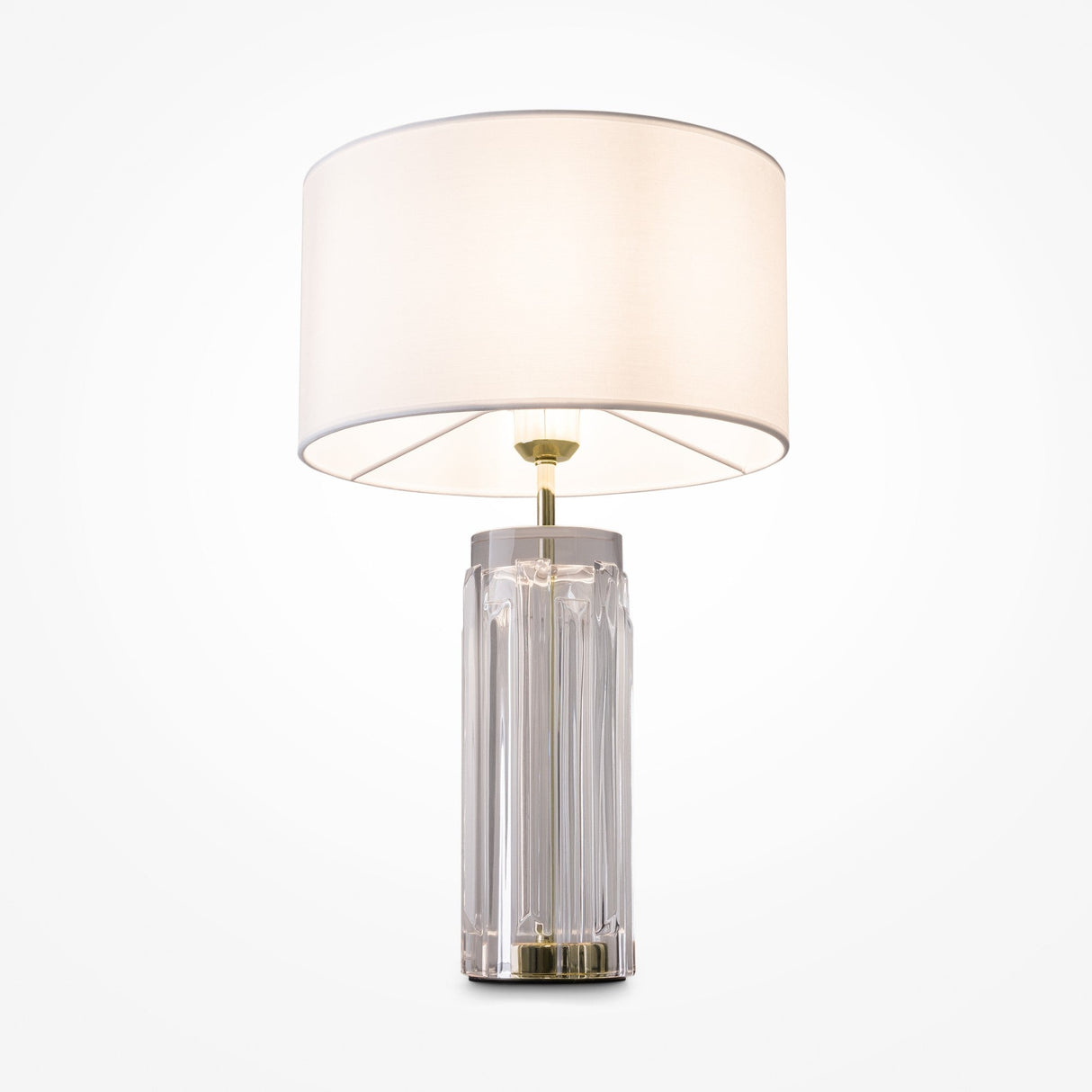 The Muse Table Lamp - Gold With White Shade boasts a modern design with a cylindrical glass base and subtle gold accents, topped with a large white fabric shade. It stands elegantly against a white backdrop, seamlessly blending style and simplicity.