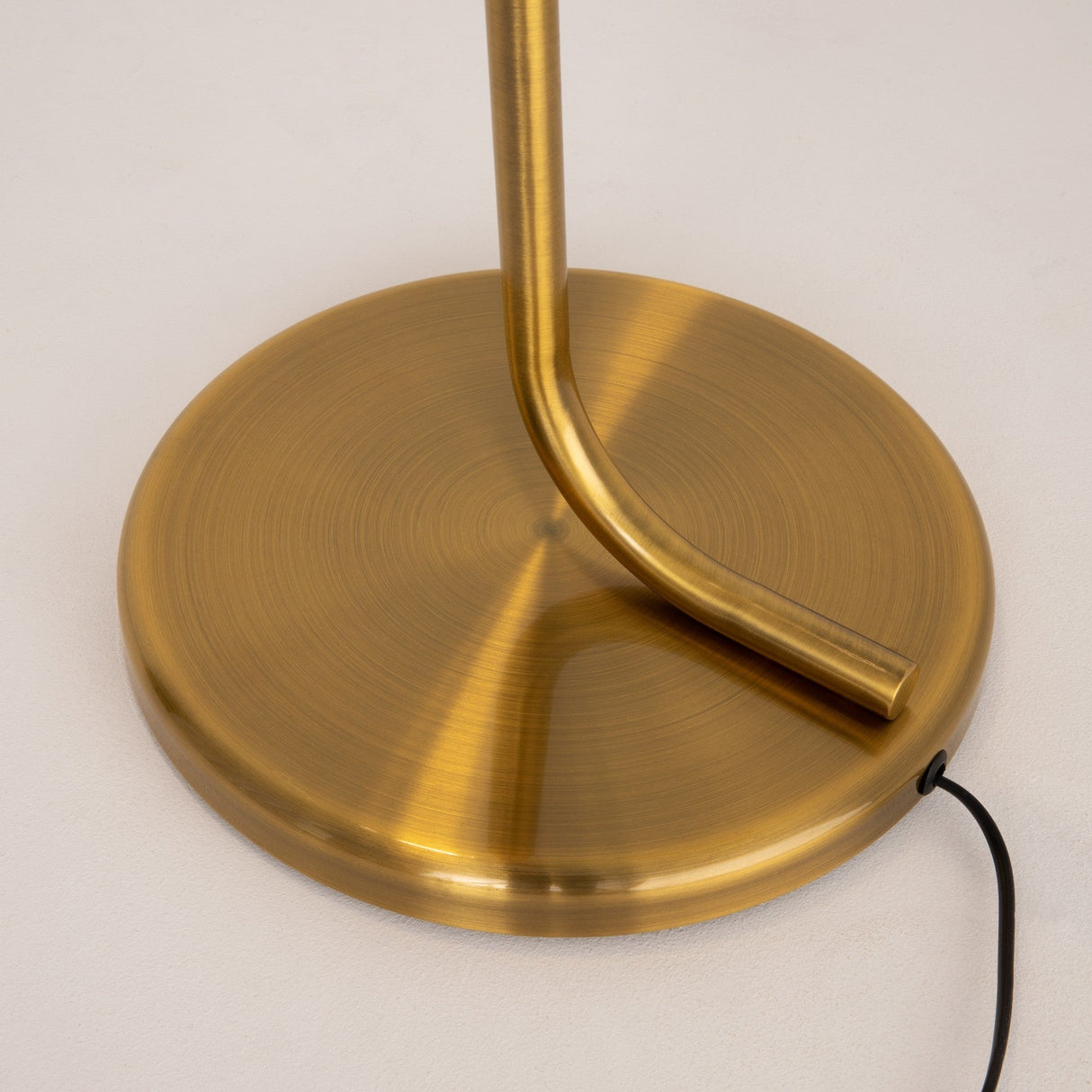 The image reveals the base of the Cabaret LED Floor Lamp - Brass, showcasing its sleek cylindrical shape in a modern gold finish. It features advanced LED technology, with a subtle power cord visible against a neutral backdrop.